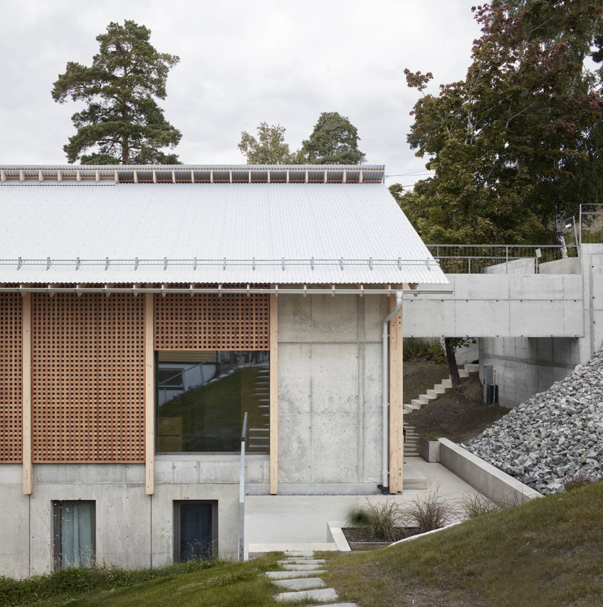 一座現代住宅建築外觀,擁有混凝土立面、木質裝飾與金屬欄杆。