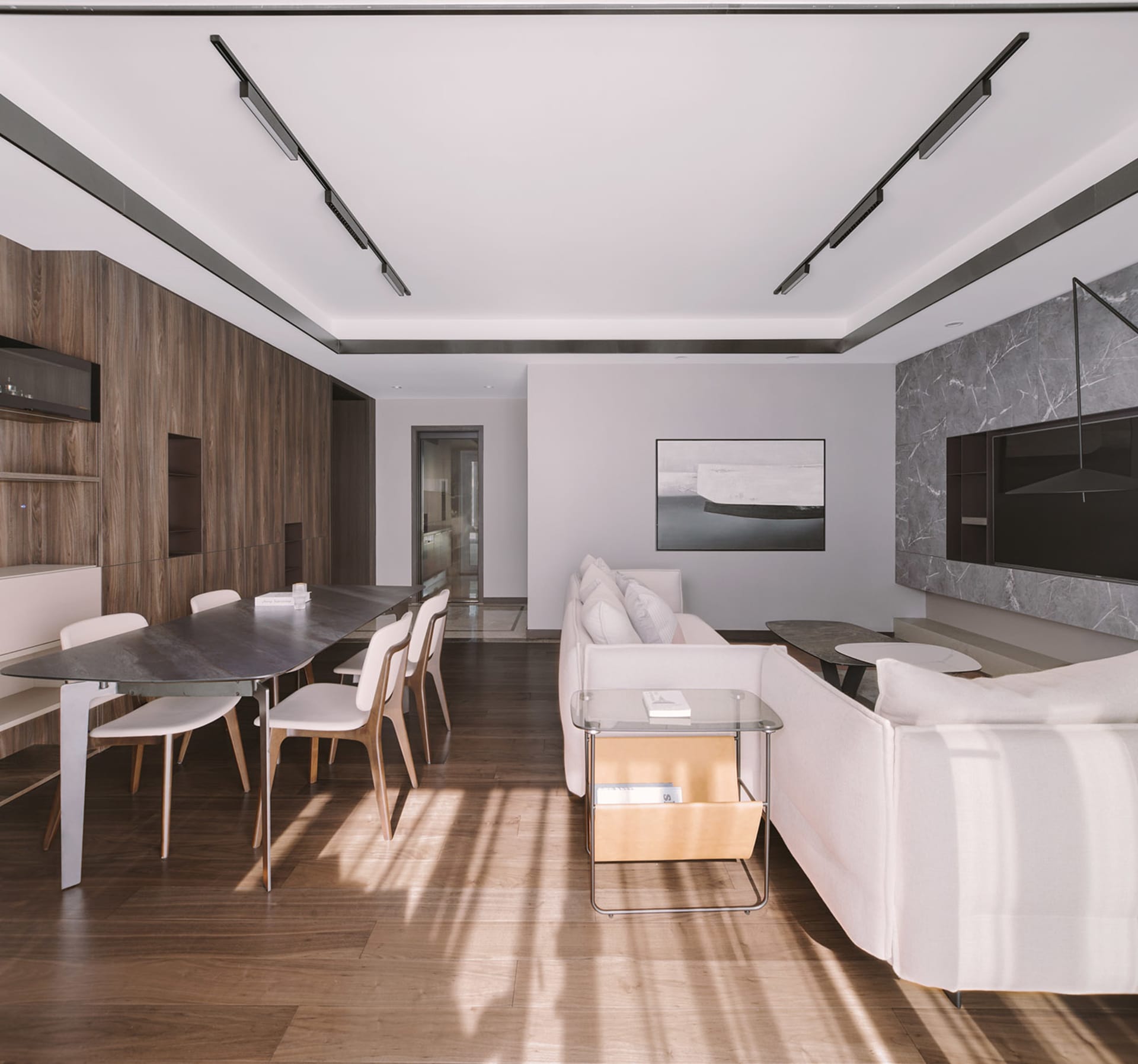 A modern living room with a wooden floor, marble walls, metal light fixtures, and a fabric sofa.