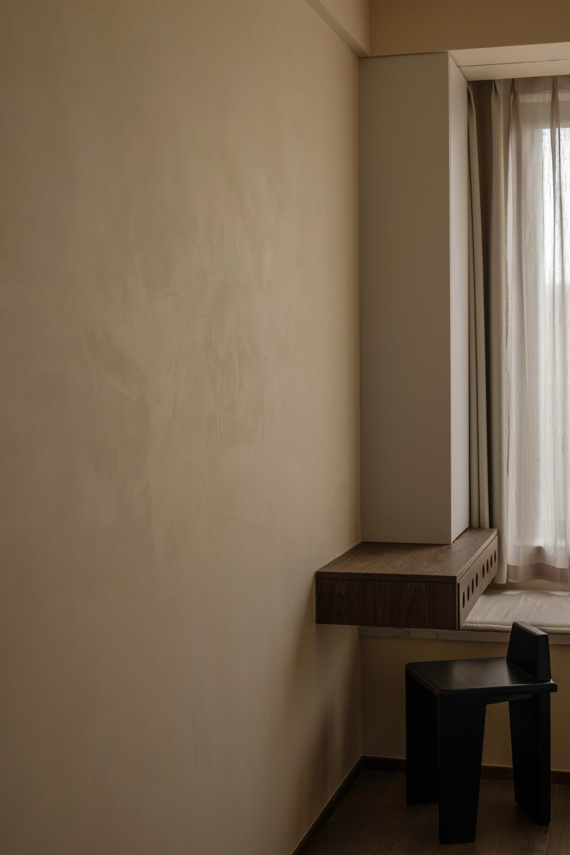 A minimalist home office space featuring a dark wood-paneled wall with a modern, sleek desk.