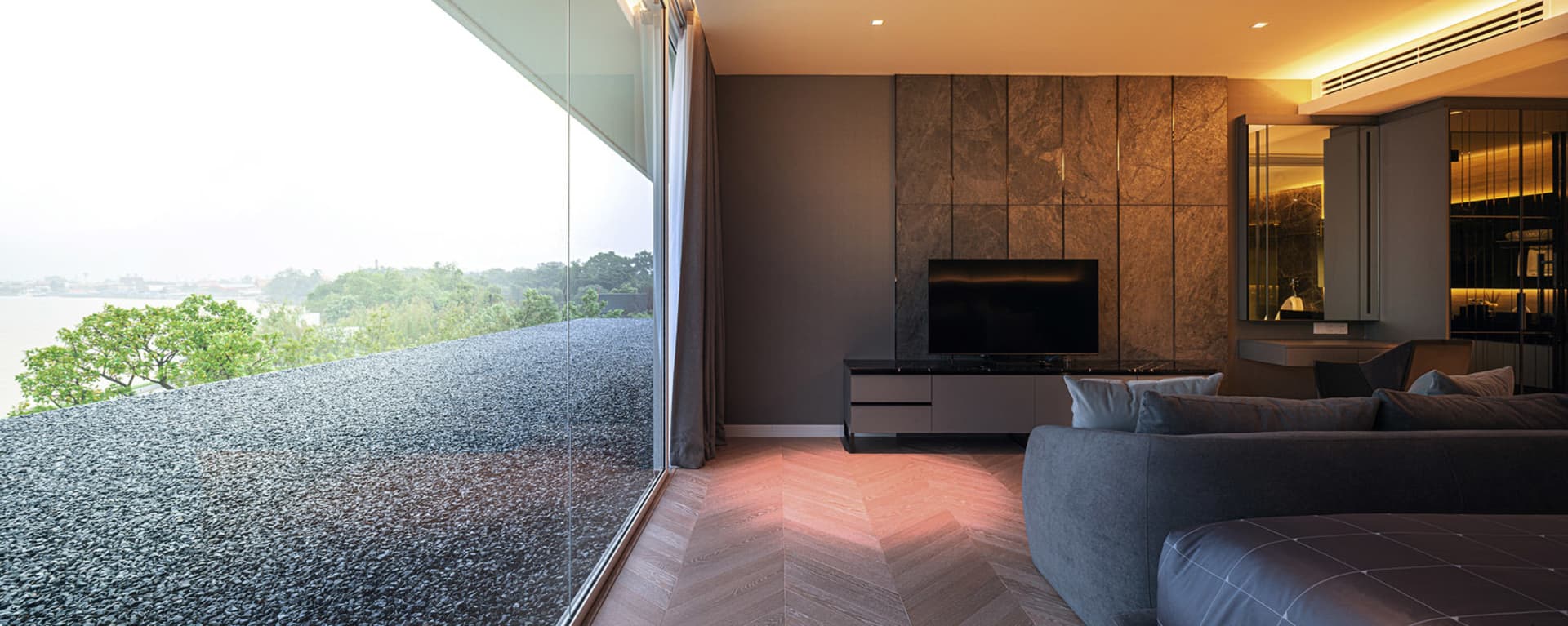 Modern living room featuring concrete, glass, and wood materials with herringbone flooring