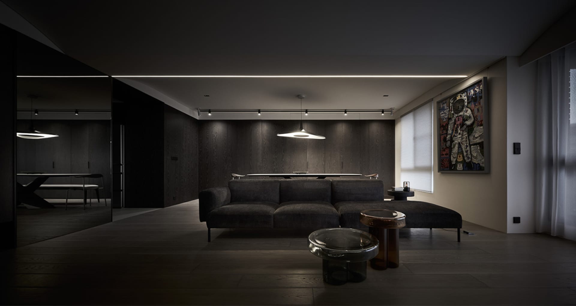 A modern living room with dark interior design, featuring dark wood flooring, dark sofas, and minimalist decor.