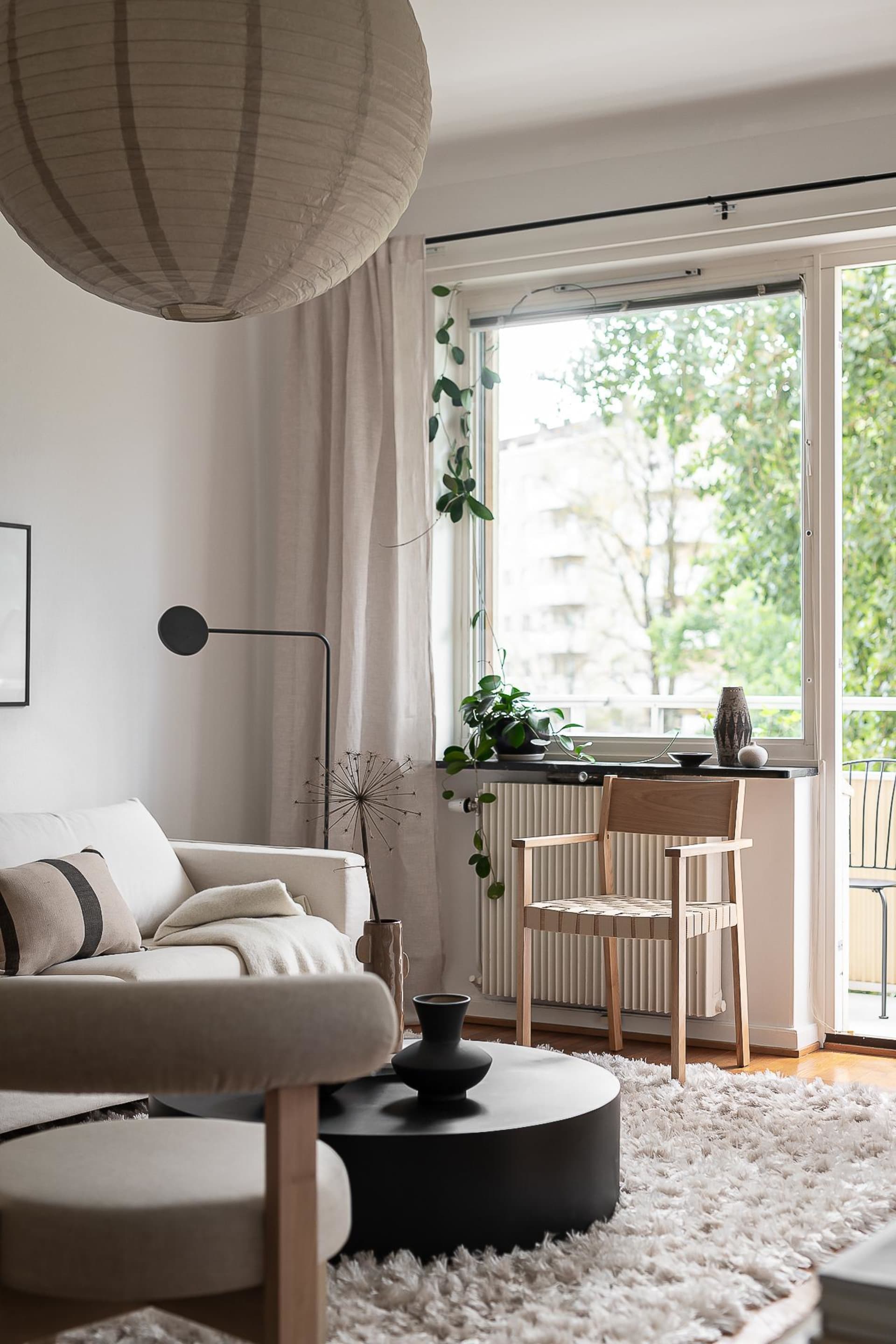 A minimalist living room featuring a couch, coffee table, and window with greenery outside.