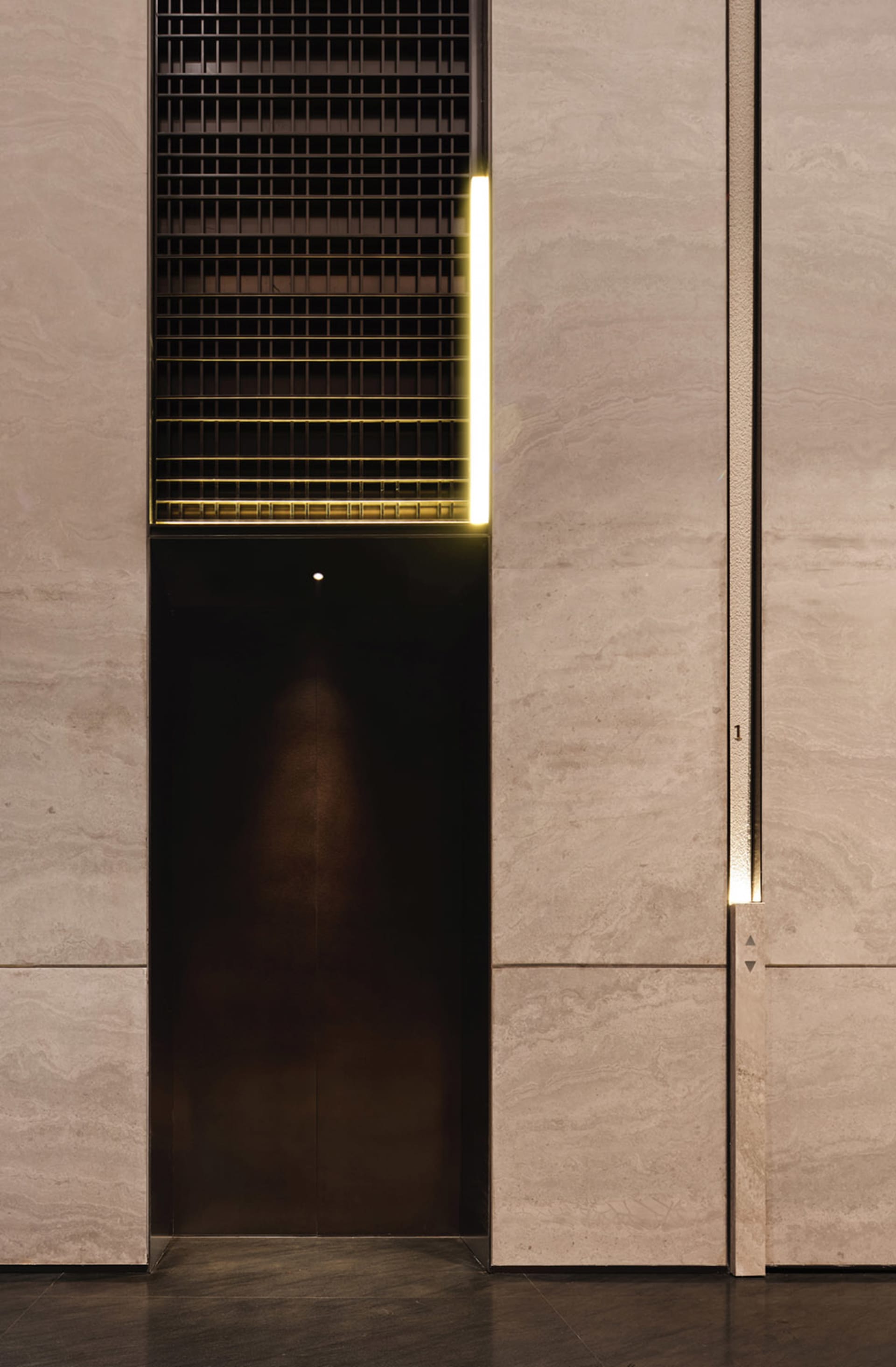 Modern elevator interior featuring metallic and stone materials