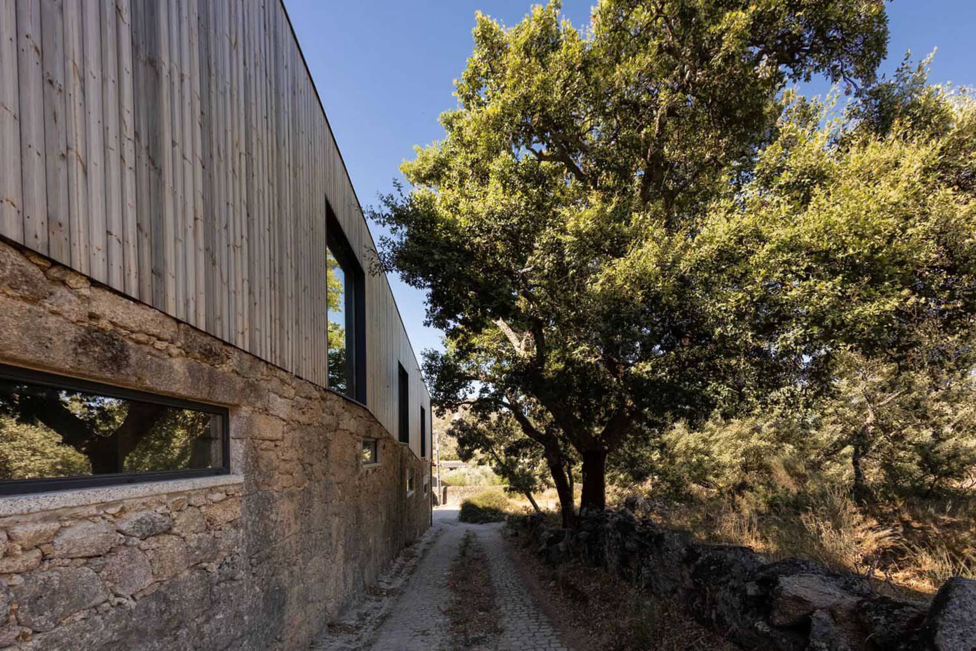 A modern farmhouse exterior with wood siding and stone foundation.