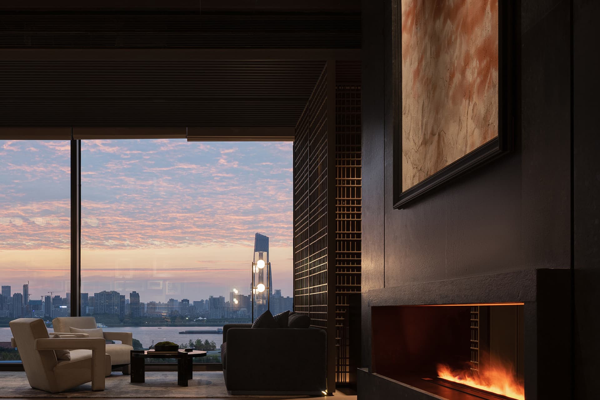 A modern living room featuring a fireplace with a cityscape sunset view.