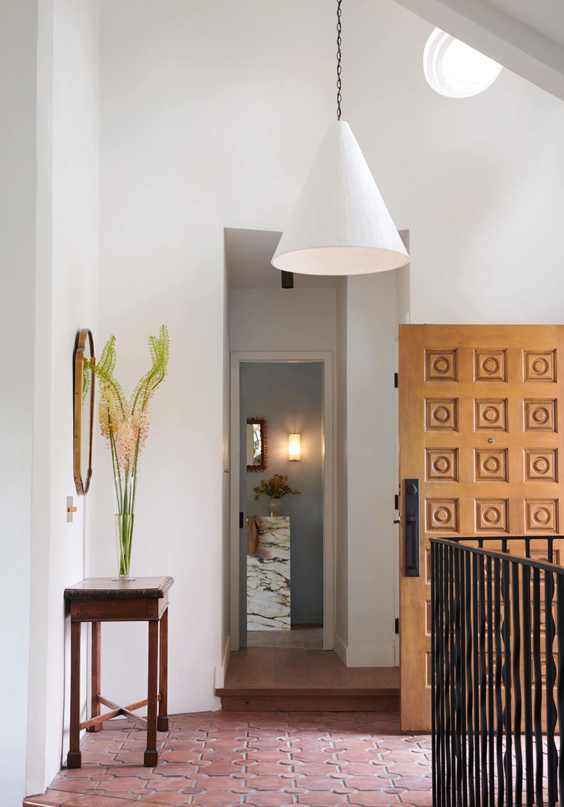Modern entryway with floor of terrazzo and cement, featuring a wooden door with geometric design.