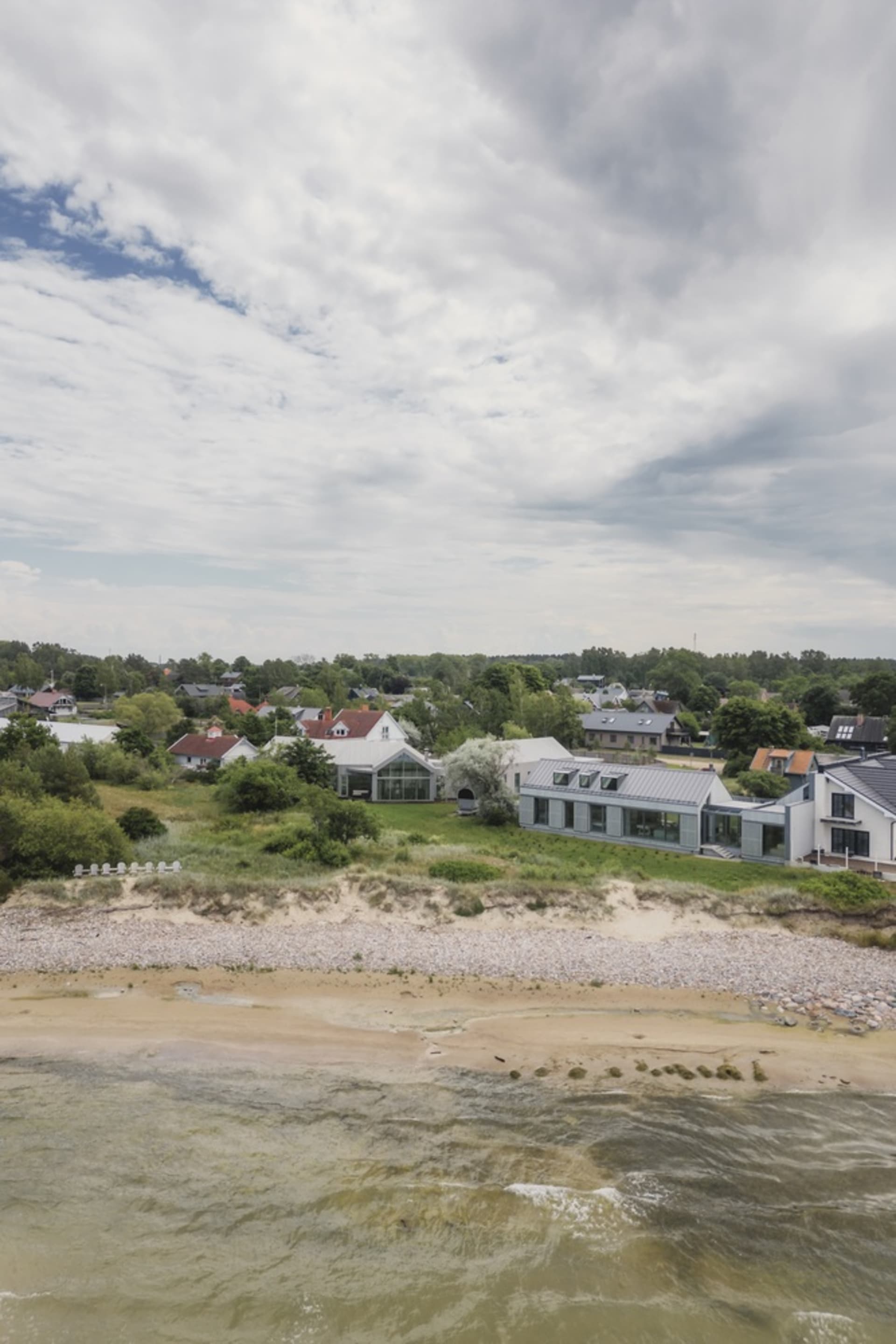 A coastal town with modern beach homes featuring glass, wooden, and metallic architectural elements.