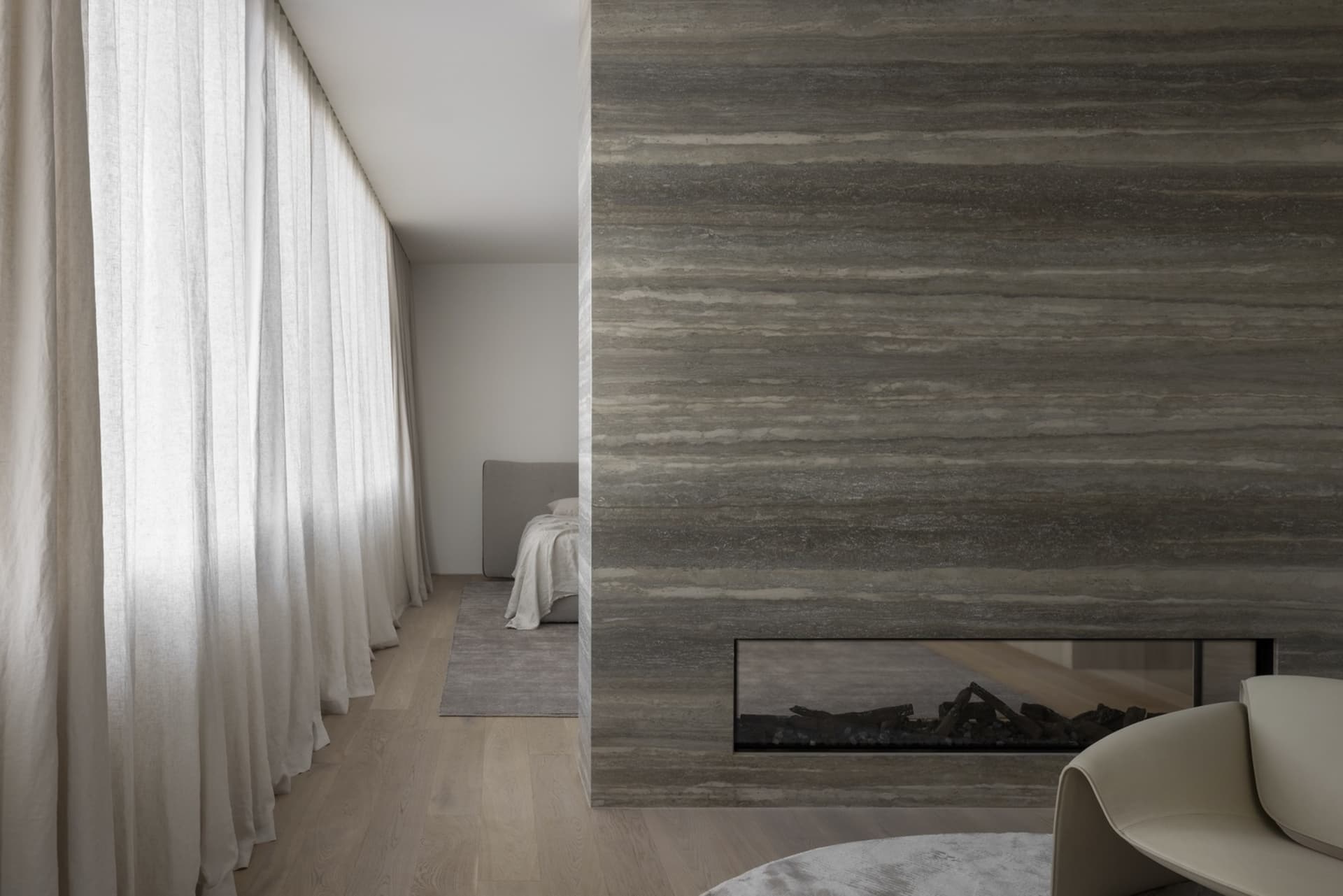 Modern minimalist bedroom featuring a concrete fireplace with a neutral color palette and minimalistic design.