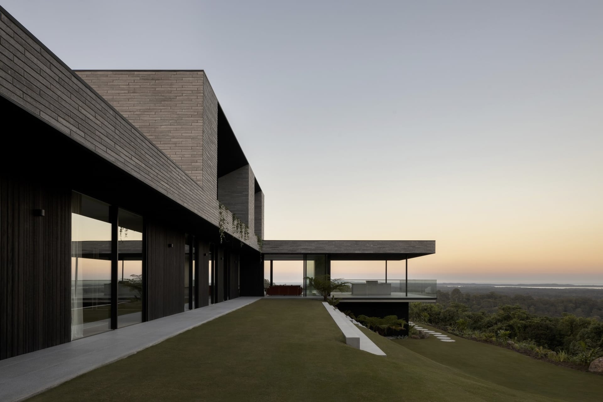 Modern residential building with large windows and a sloping roofline.