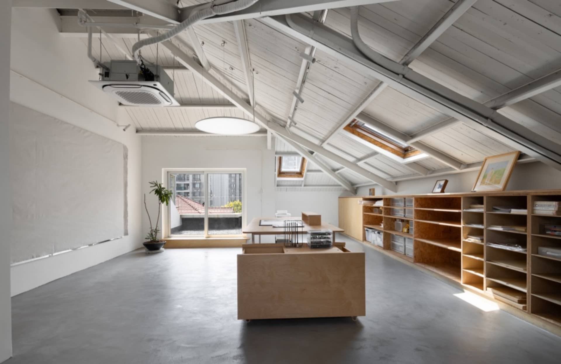 Modern, open-concept office space with industrial design elements, concrete flooring, wooden furniture, and white walls.