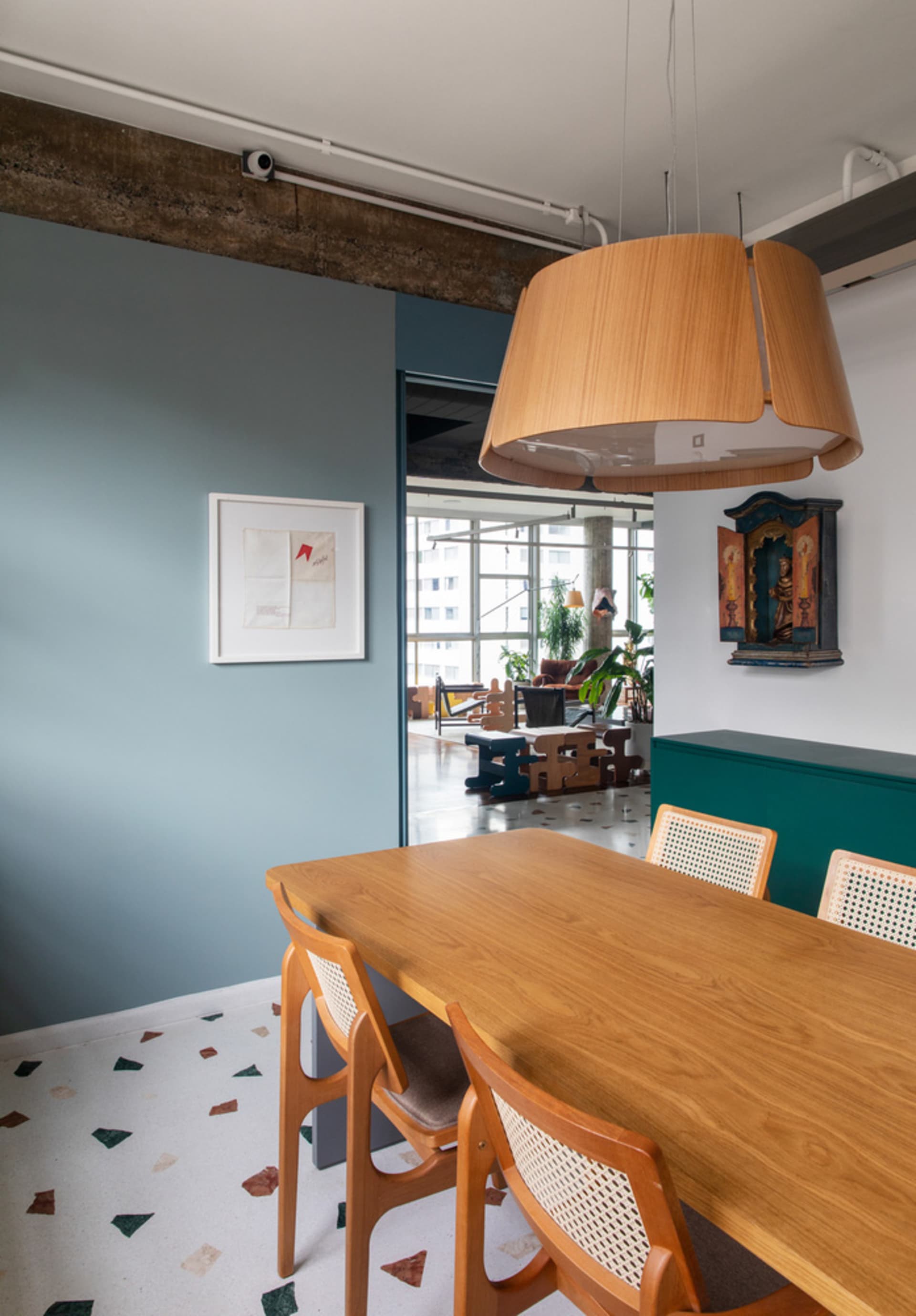 Modern interior design featuring a wooden dining table and chairs in a room with green and white flooring, and a large pendan