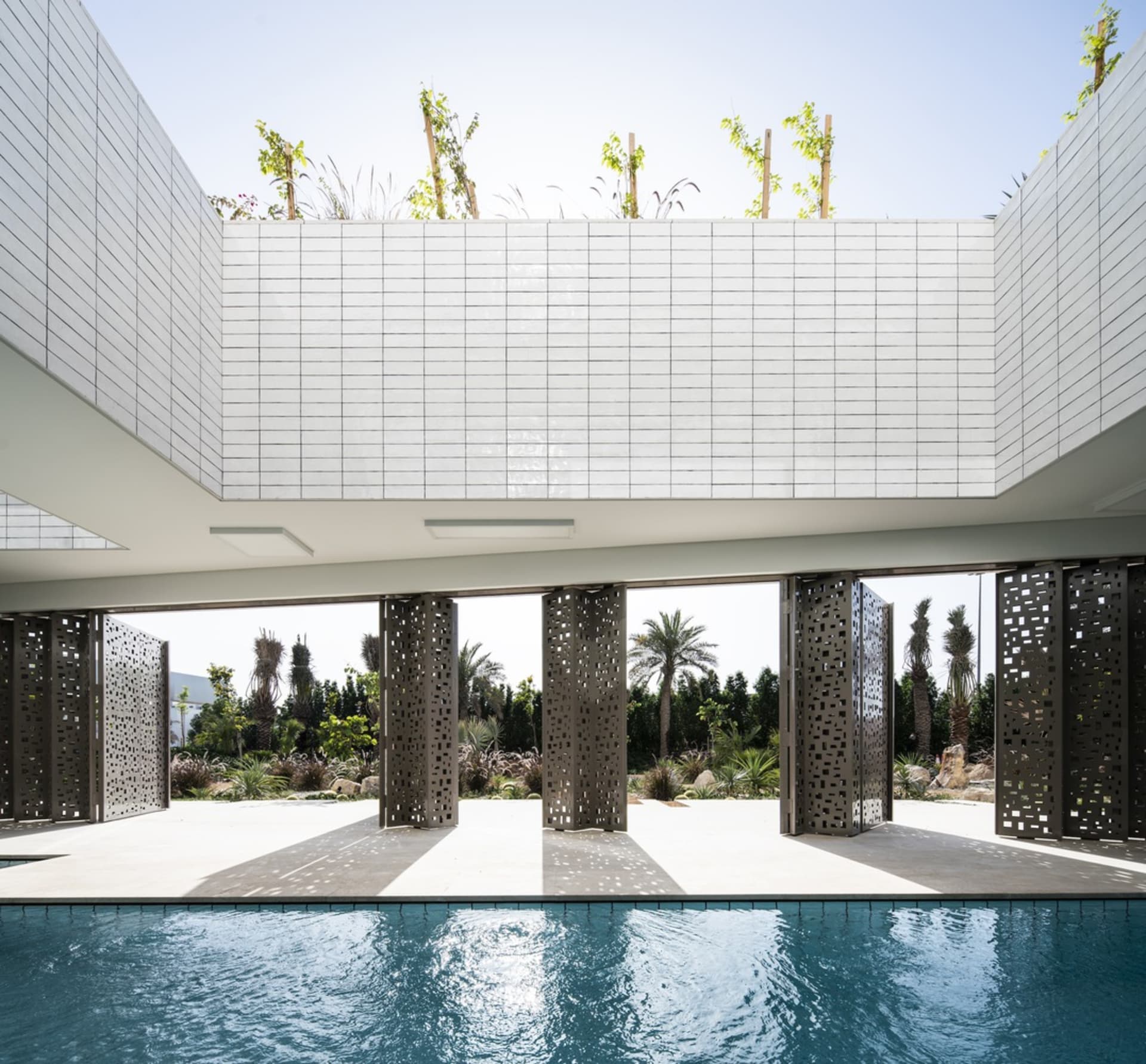A modern pool house with white materials and metal tiles