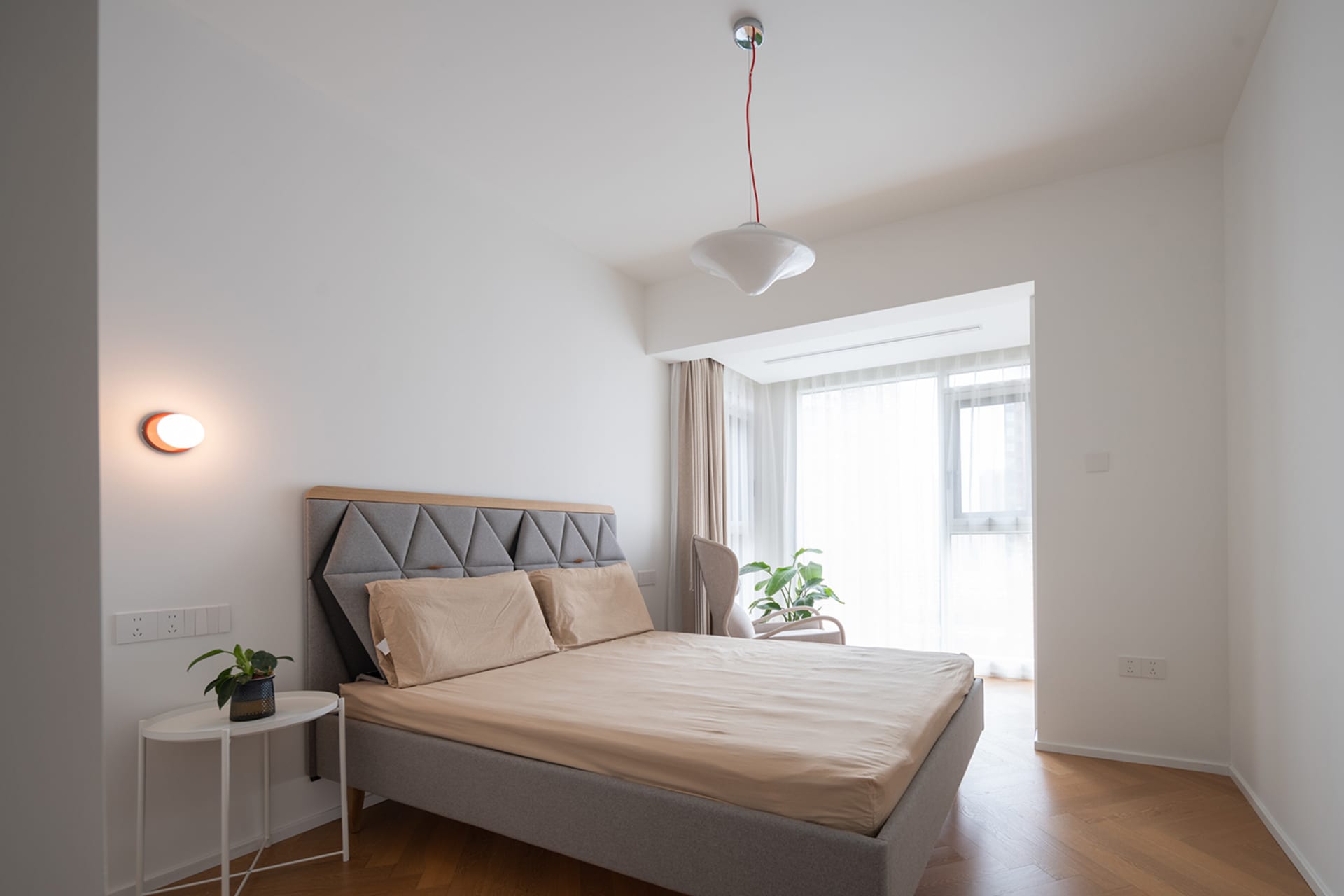 Minimalist bedroom with fabric bed and wooden floor.