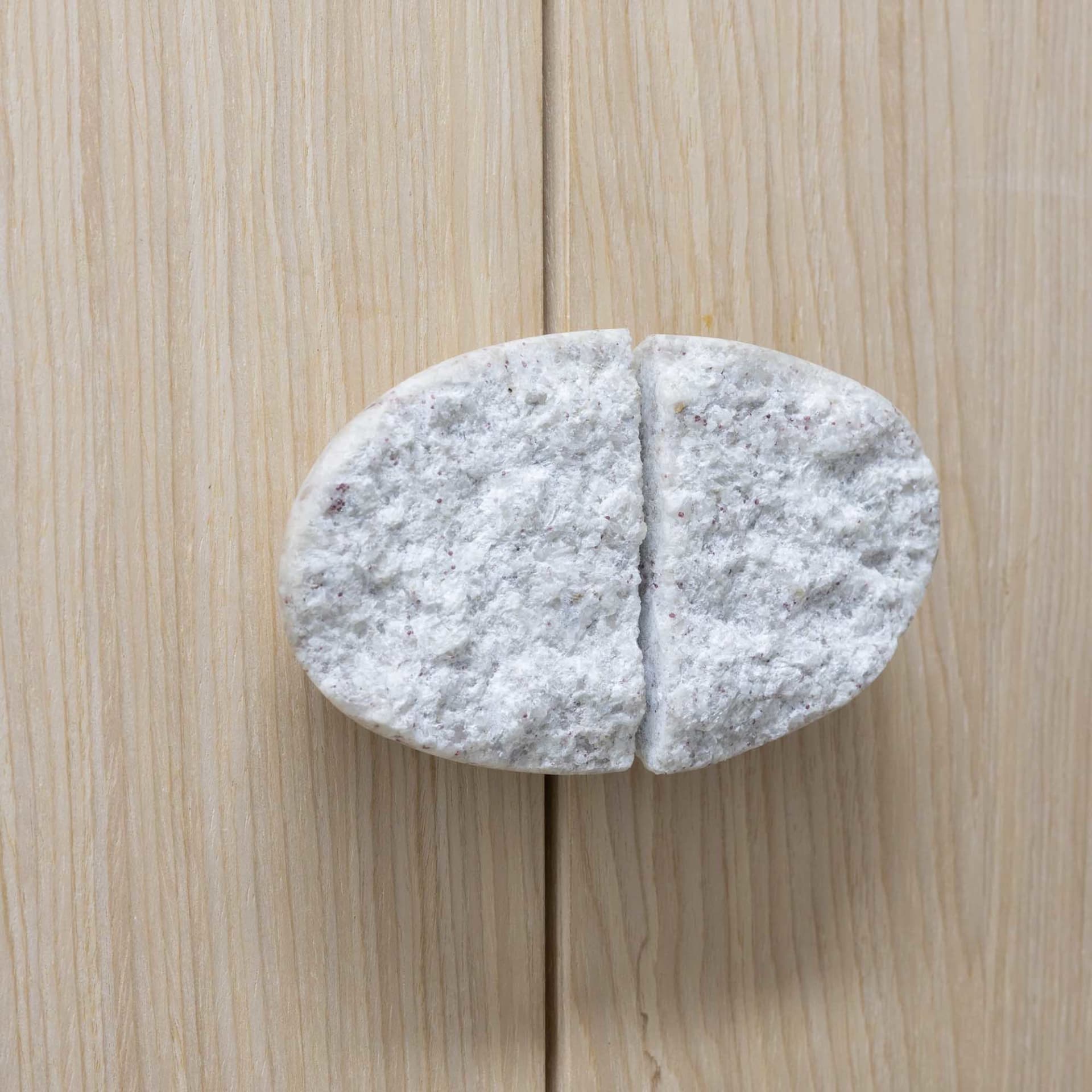 A modern, oval-shaped marble door handle attached to a light-colored wooden door.