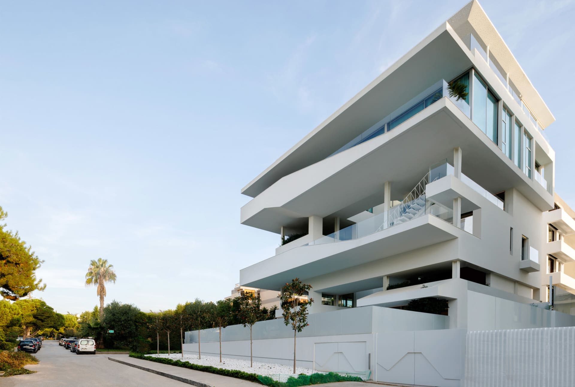 Modern apartment building with white concrete exterior and large balconies.