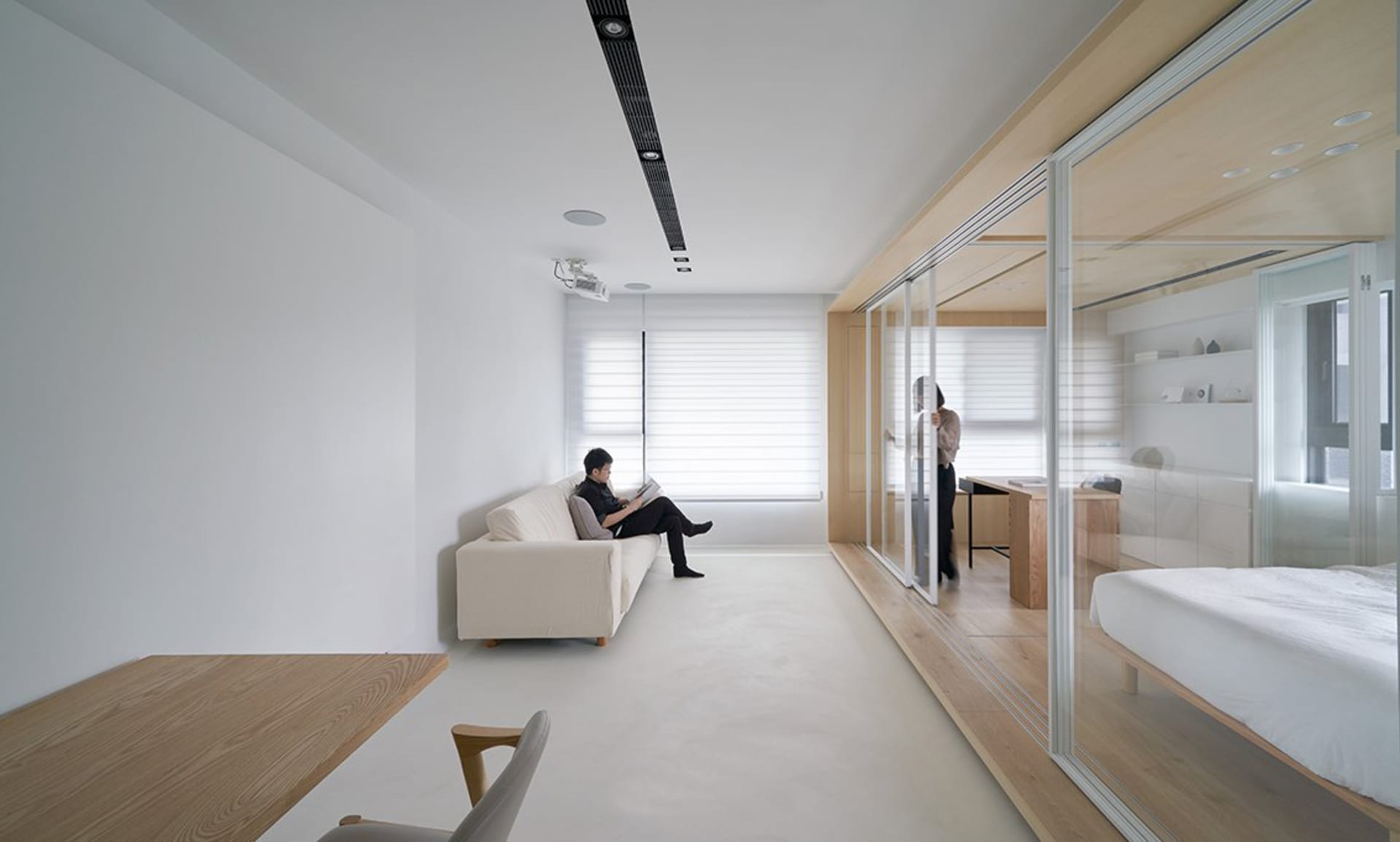 Modern minimalist living room with white furniture, wood accents, and white walls.