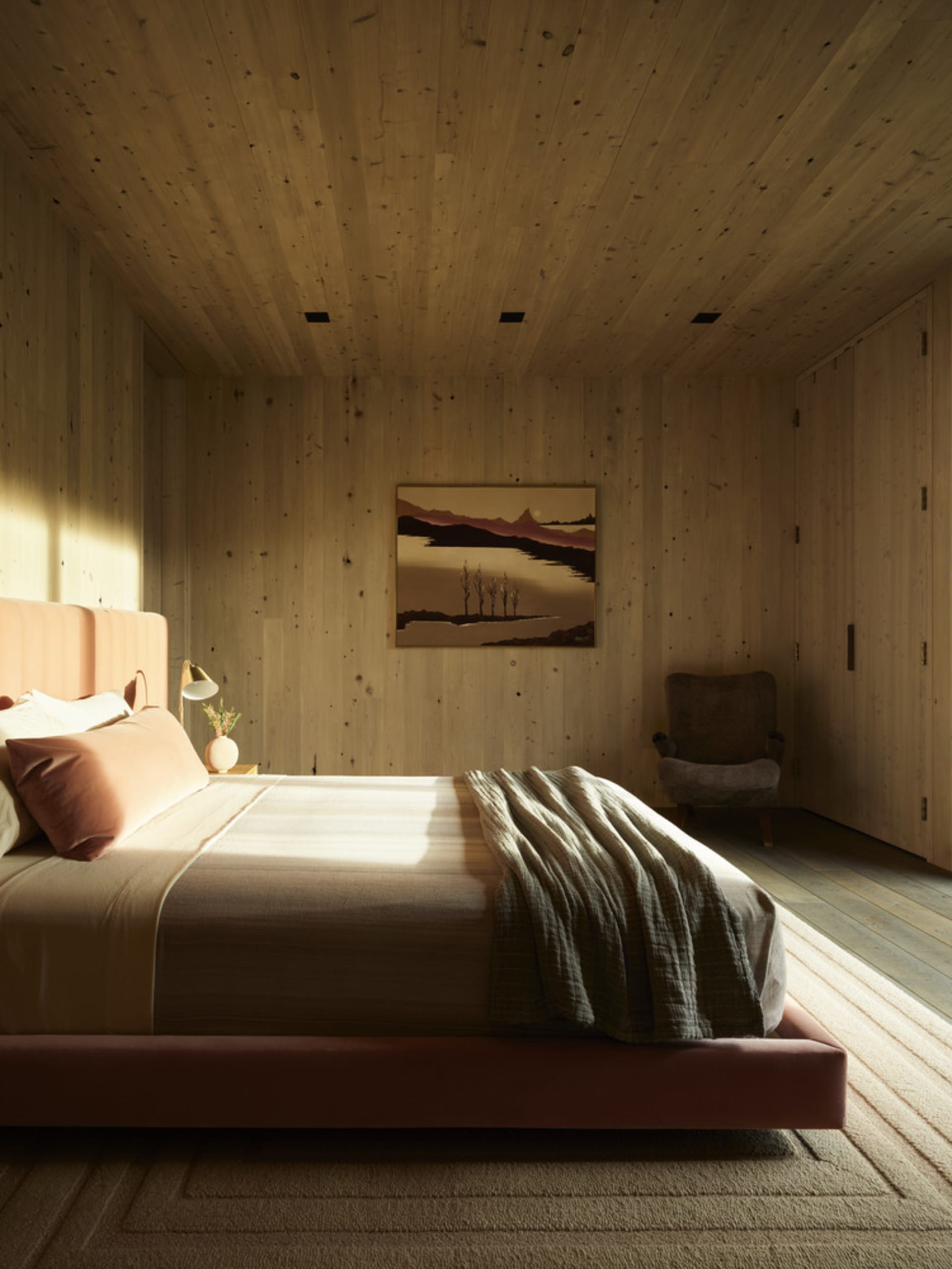A modern bedroom with wooden walls, featuring a wooden bed and a painting on the wall.