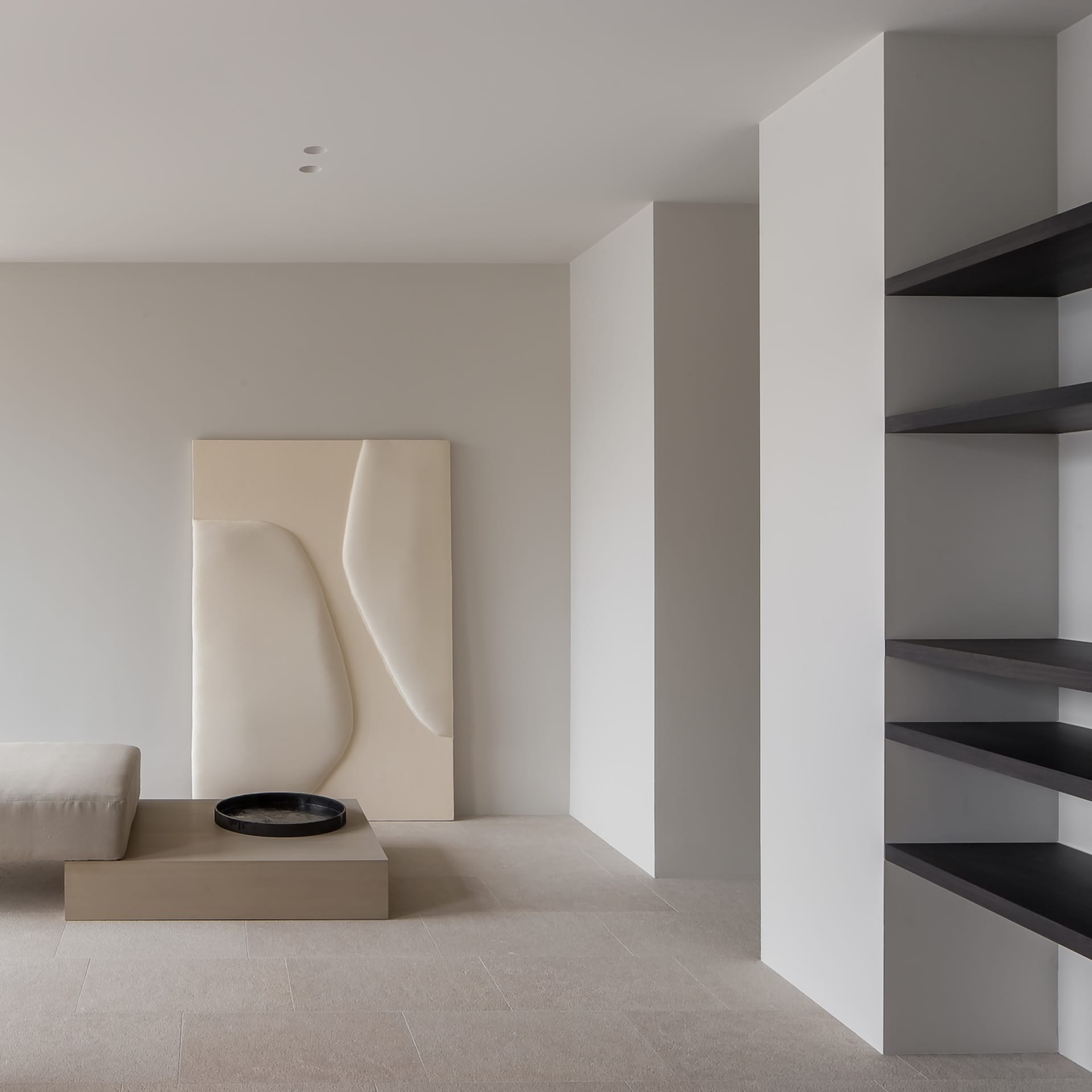 A minimalist living room with concrete walls and furniture.