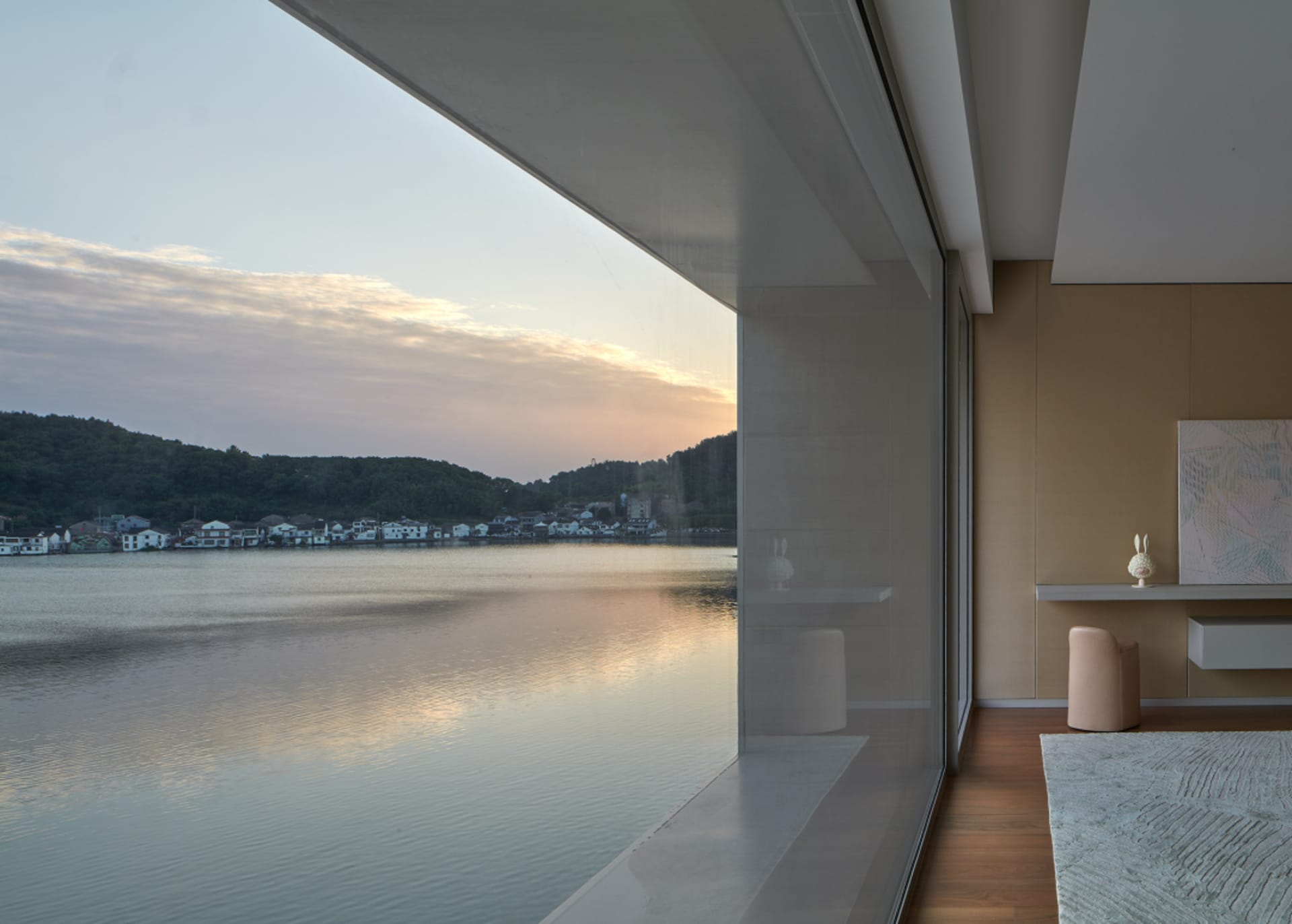 Minimalist living room with floor-to-ceiling windows overlooking a serene lake.
