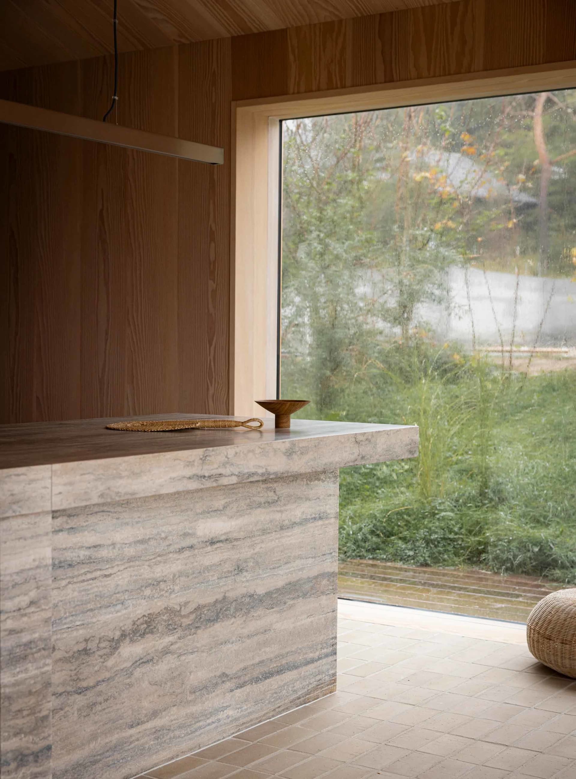 A modern interior design featuring a stone countertop with a woven rope decoration and a wooden bowl on top, framed by a larg