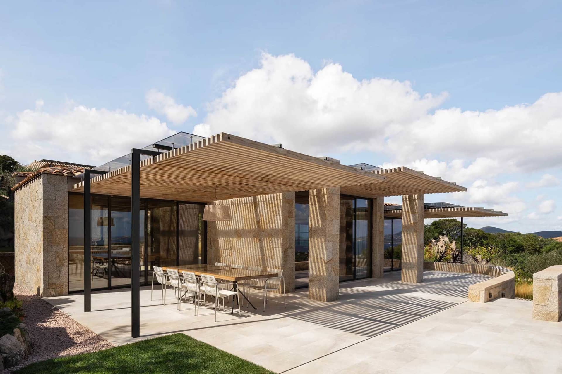 Modern residential property with wooden pergola, stone walls, and tiled patio area.