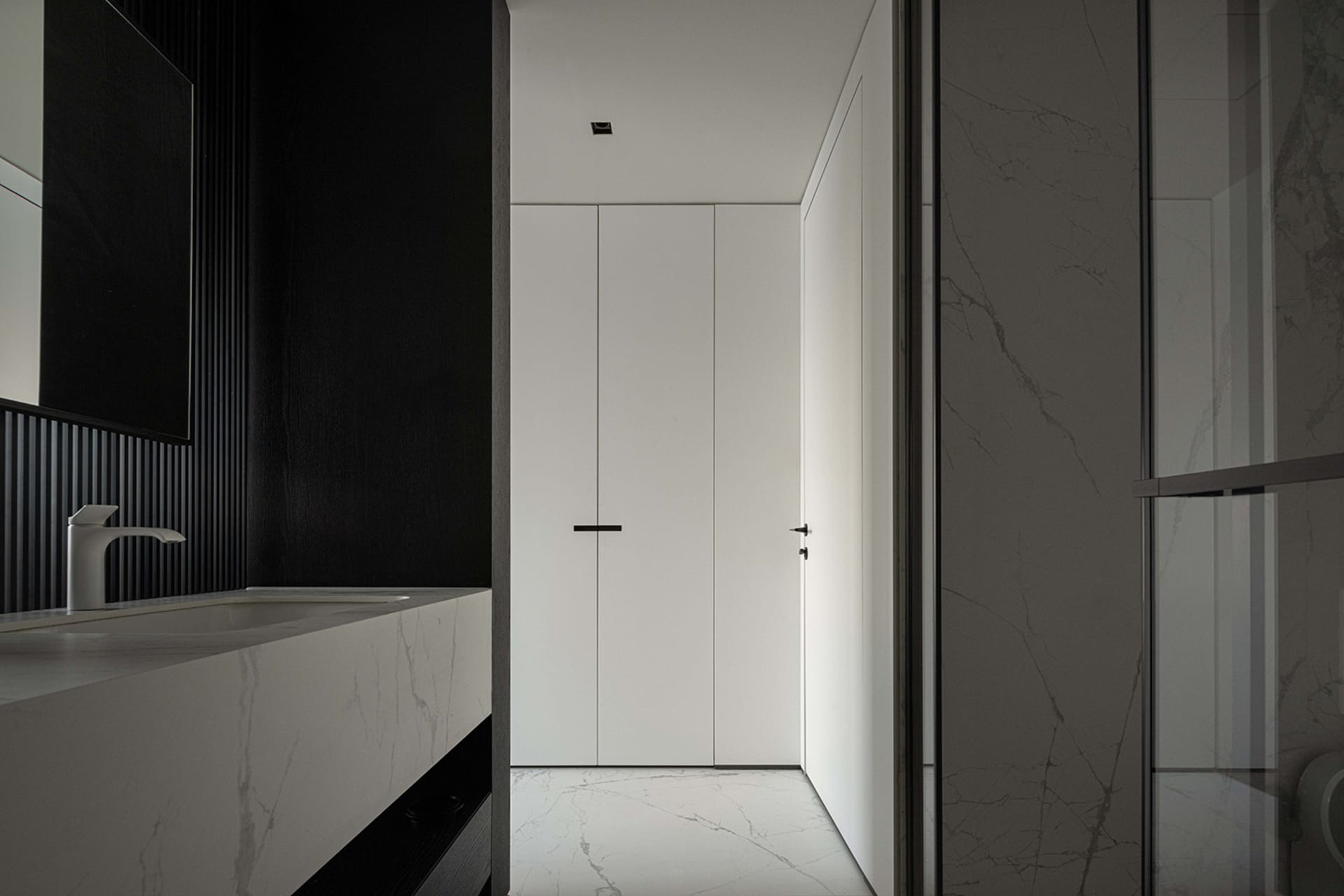 Modern minimalist white marble bathroom with sleek black accents.