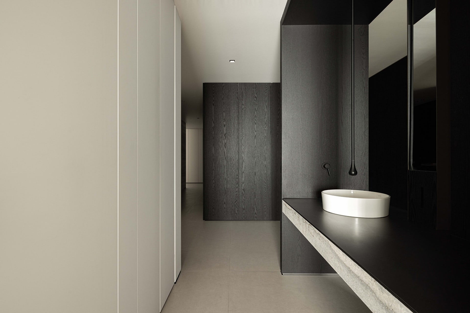 Minimalist bathroom featuring concrete sink and black wooden walls.