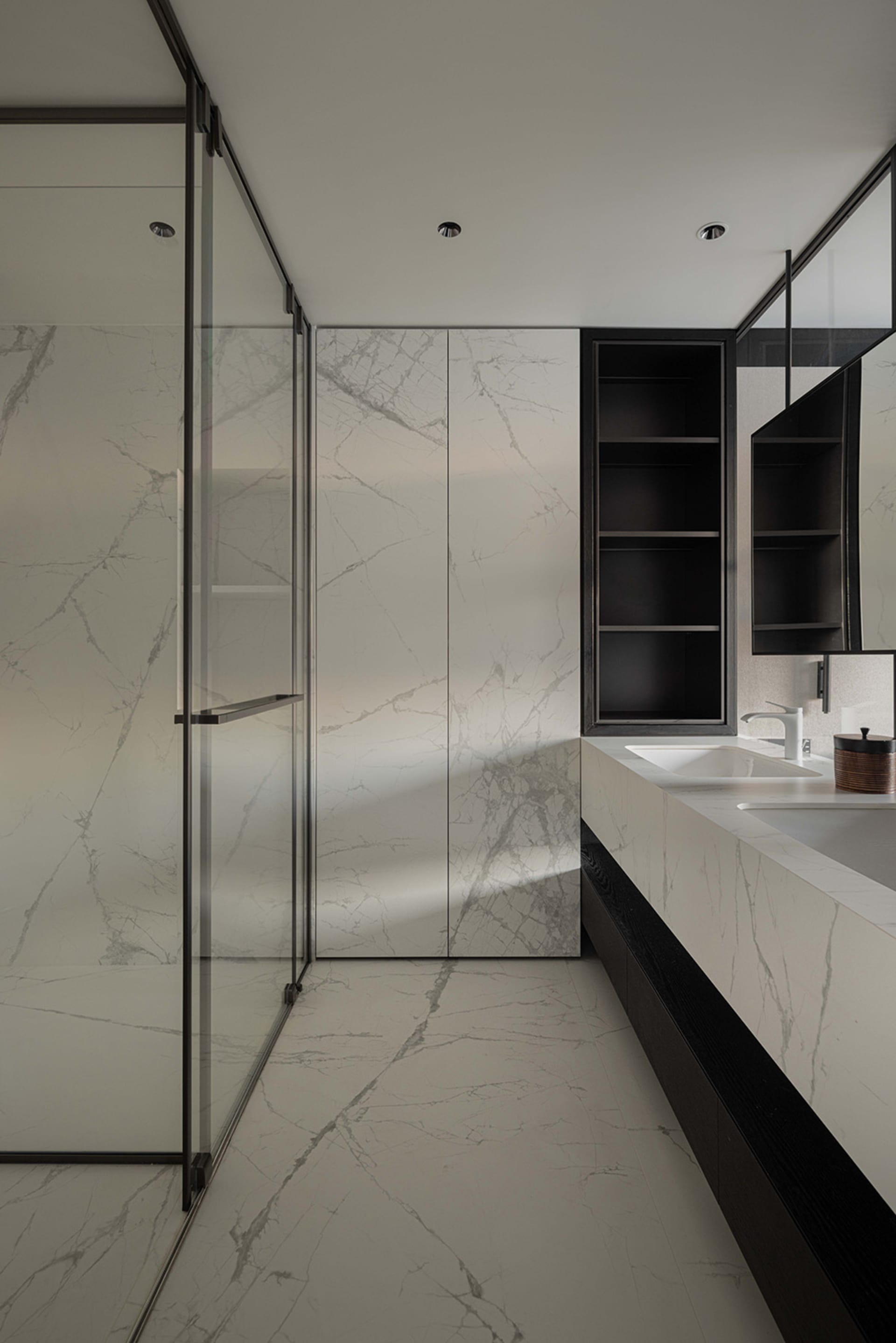 Modern bathroom with marble walls and floor, featuring a glass shower enclosure and a floating vanity.