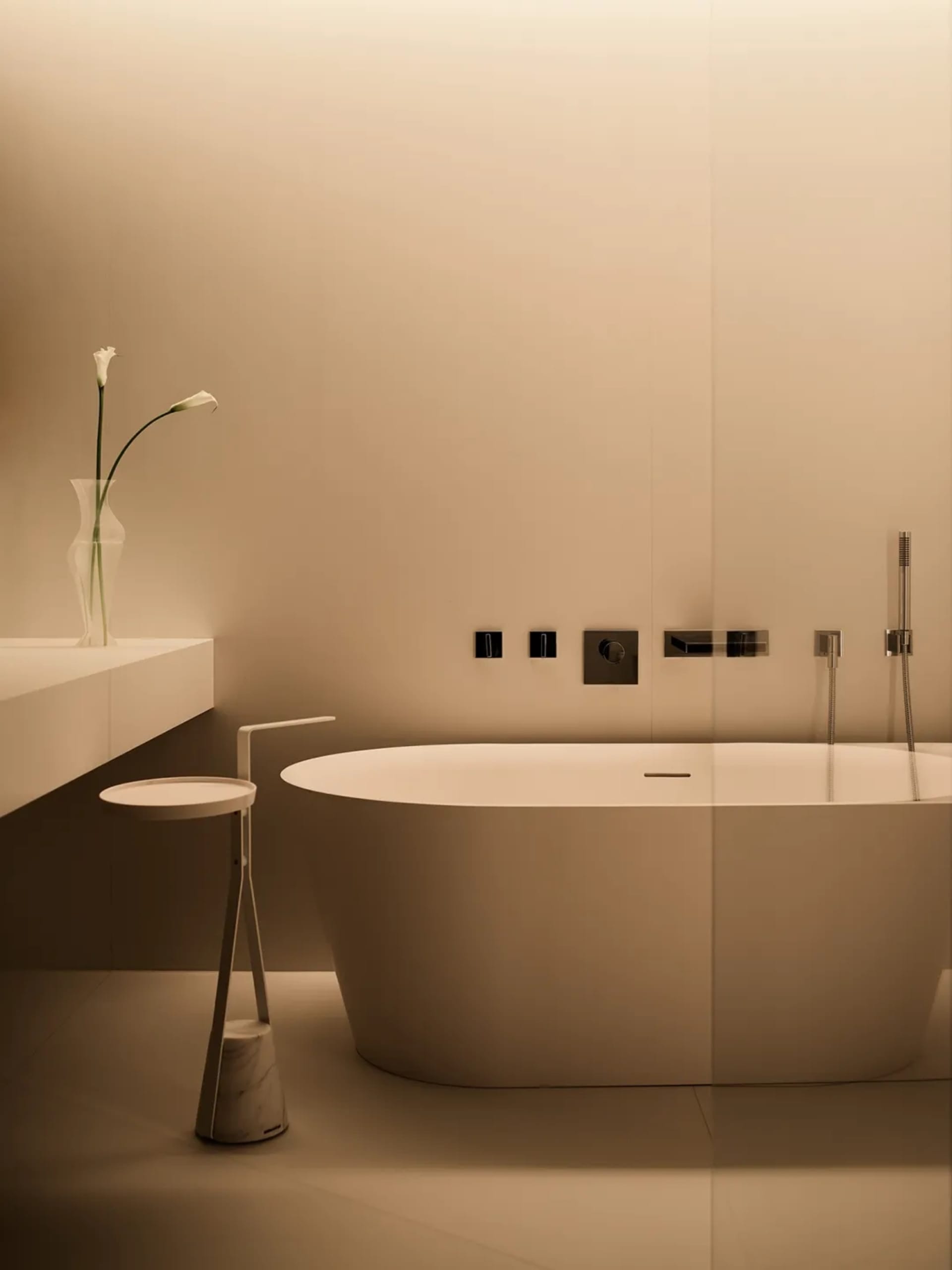 Minimalist bathroom with a concrete bathtub and vase of white flowers