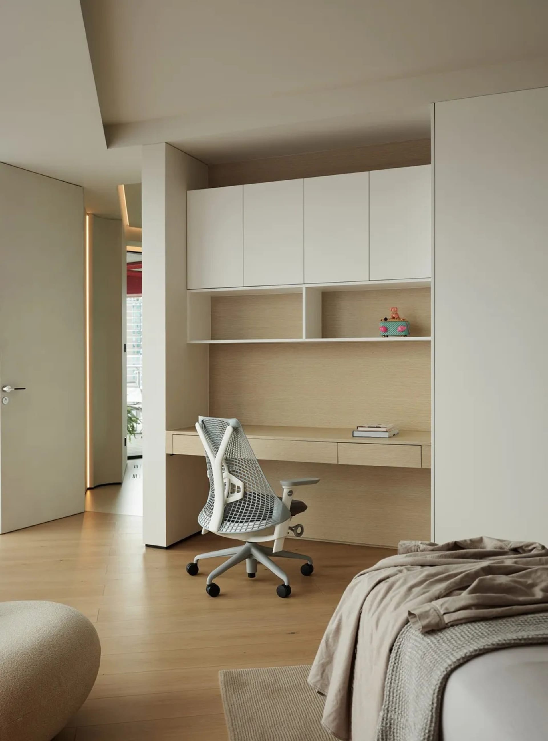 Modern minimalist master bedroom featuring a white desk with a mesh office chair, beige flooring, and light-colored wood cabi