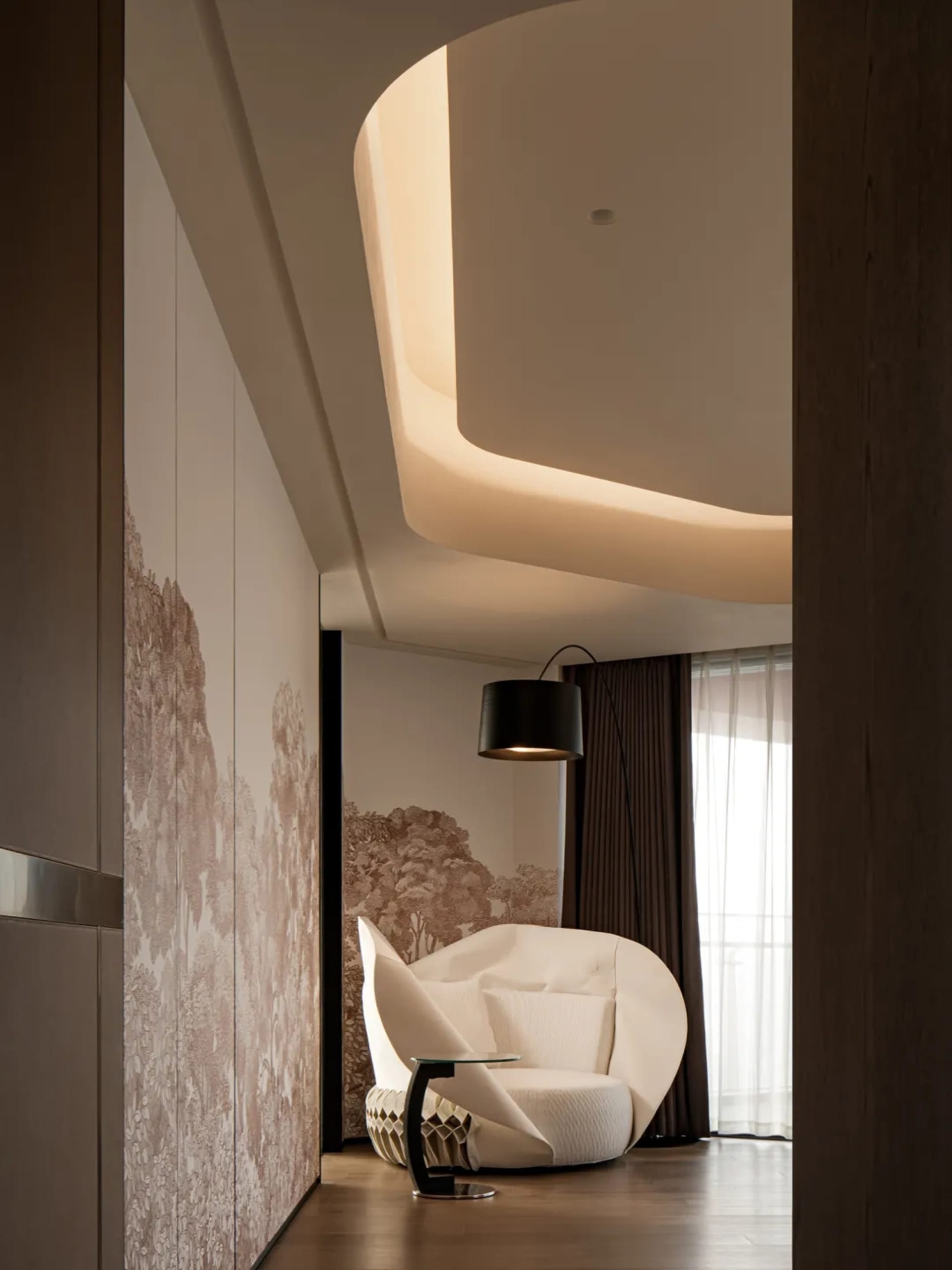 A modern residential interior featuring a plush, white, egg-shaped chair with a black floor lamp, wooden floor, and patterned