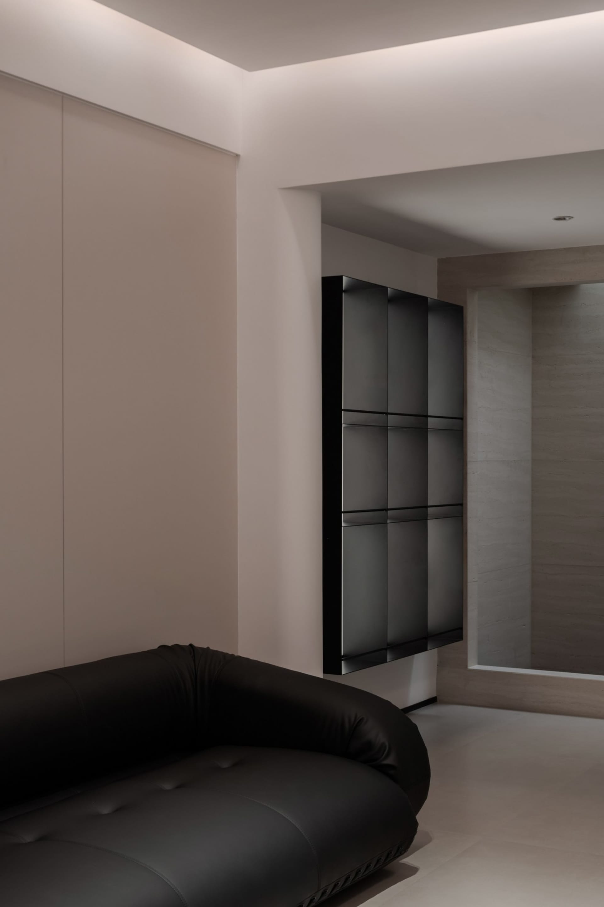 Modern minimalist living room featuring a glass cabinet and a sleek black sofa.
