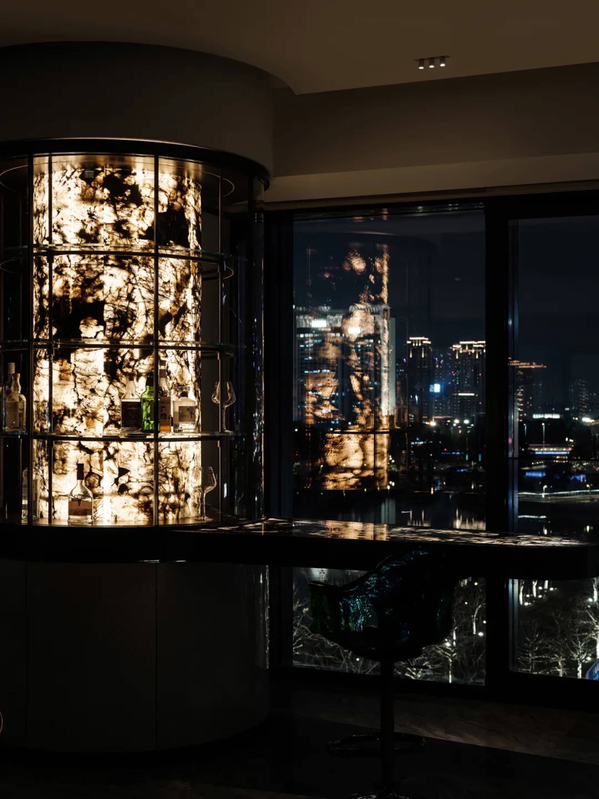 現代吧台搭配玻璃層架與燈光，夜景城市景觀映入眼簾。