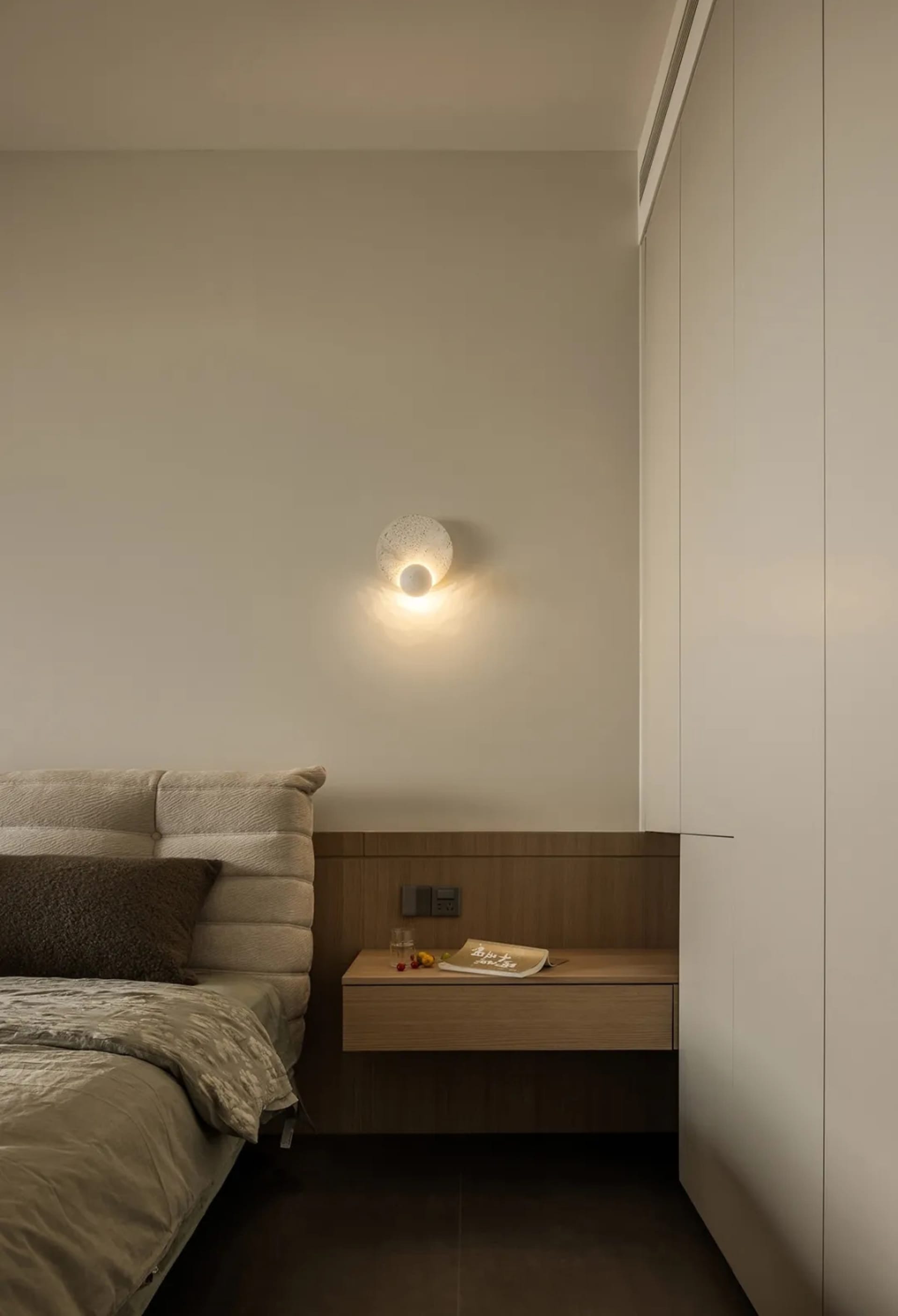 A modern minimalist bedroom with a single bed adorned with a beige textured headboard and matching cover, accompanied by a fl