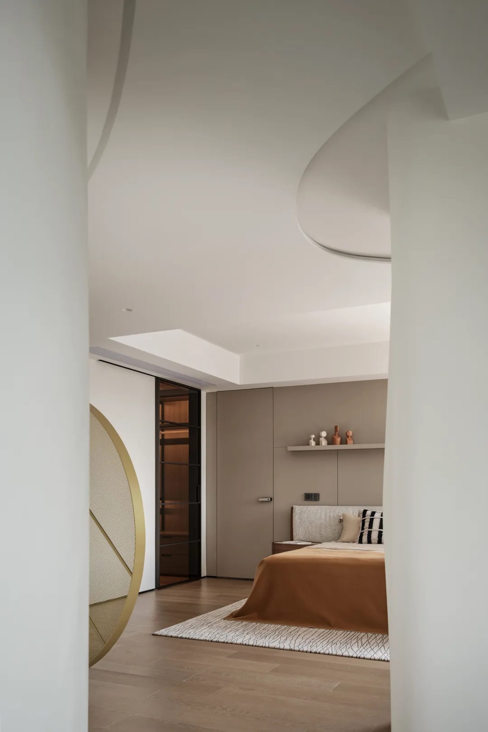A minimalist bedroom with a beige color scheme and wooden flooring, featuring a bed with a soft bedspread and pillow, and a s