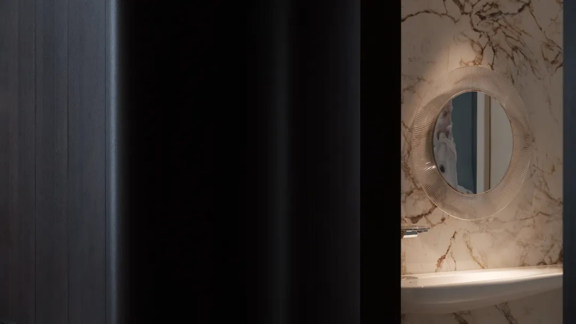 Minimalist bathroom with marble walls and glass basin.