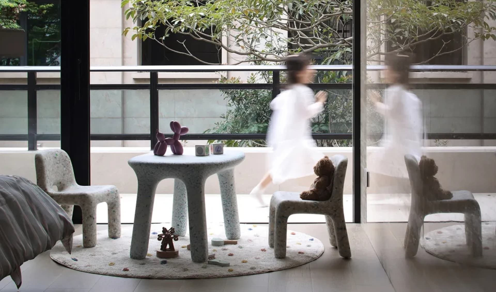 A modern playroom featuring concrete furniture and colorful toys on a round rug.