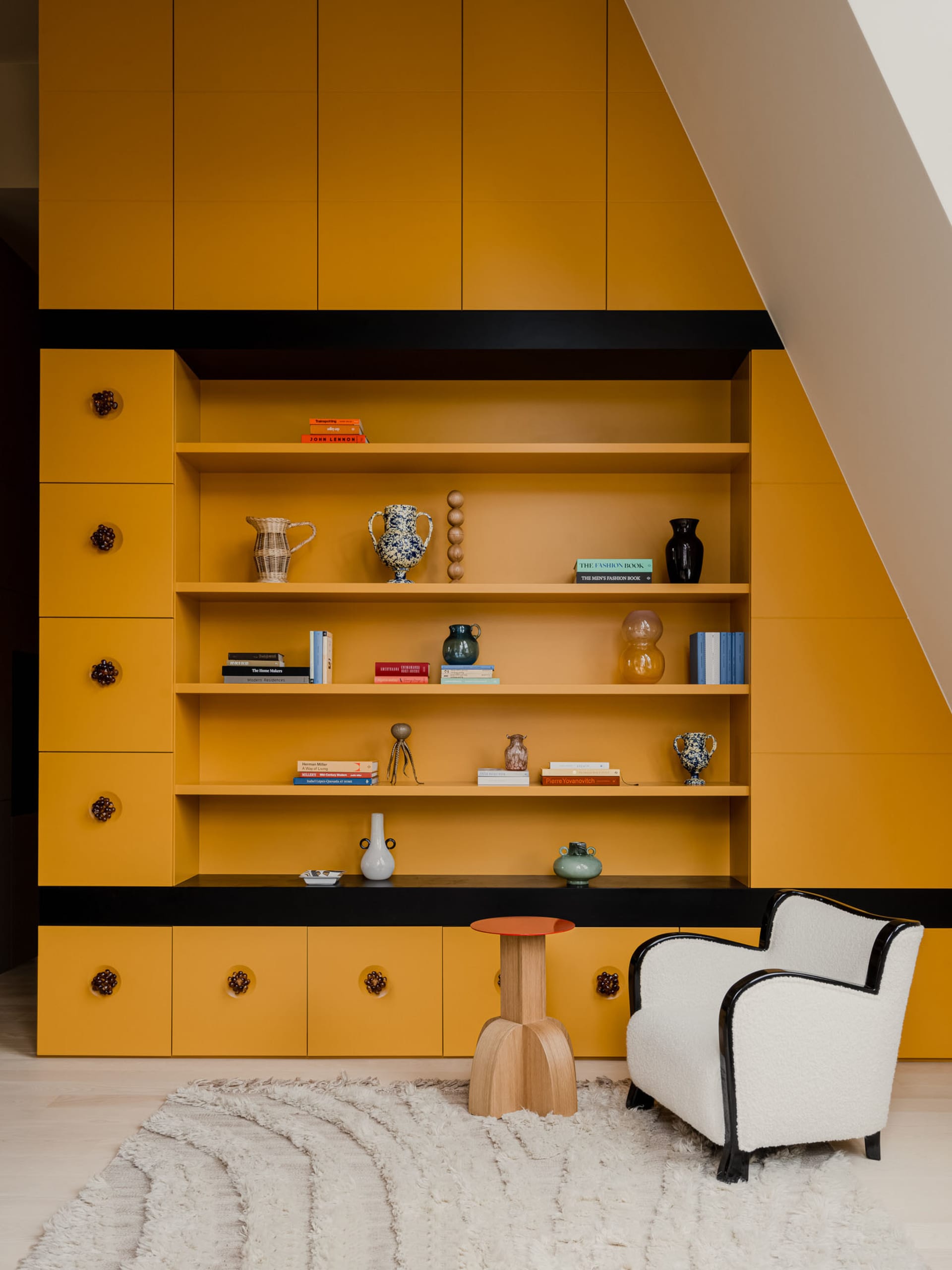 A modern living space featuring a bright yellow bookshelf and a comfortable white armchair.