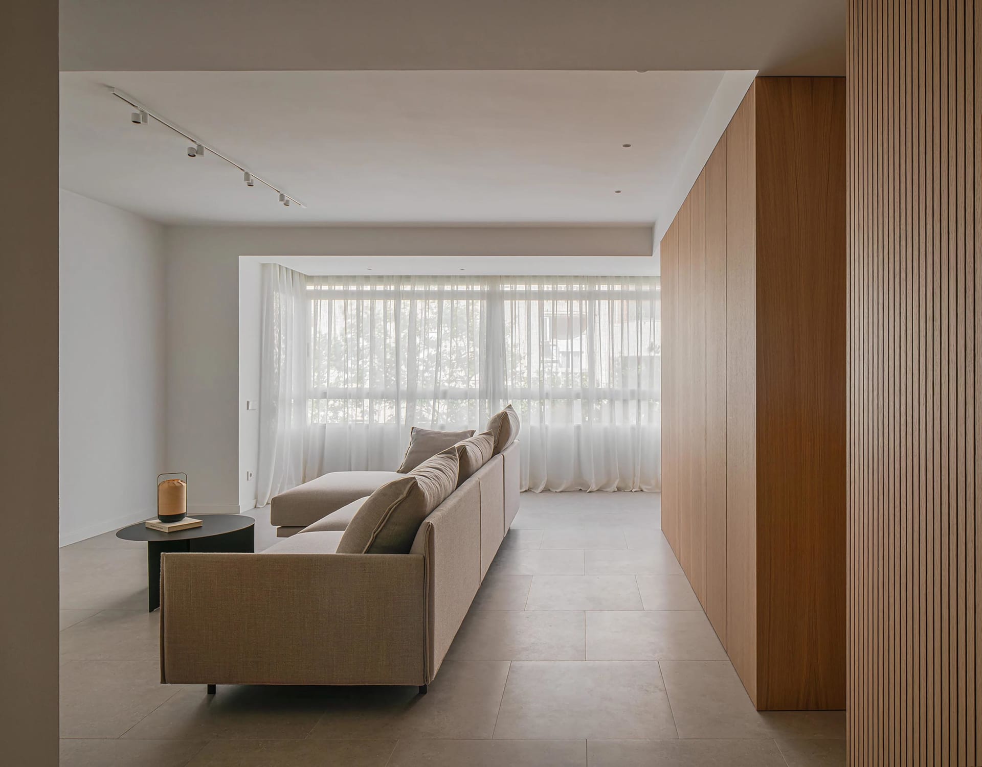 A minimalistic living room featuring a modern sofa with sandstone accents, situated in a minimalist interior design setting.