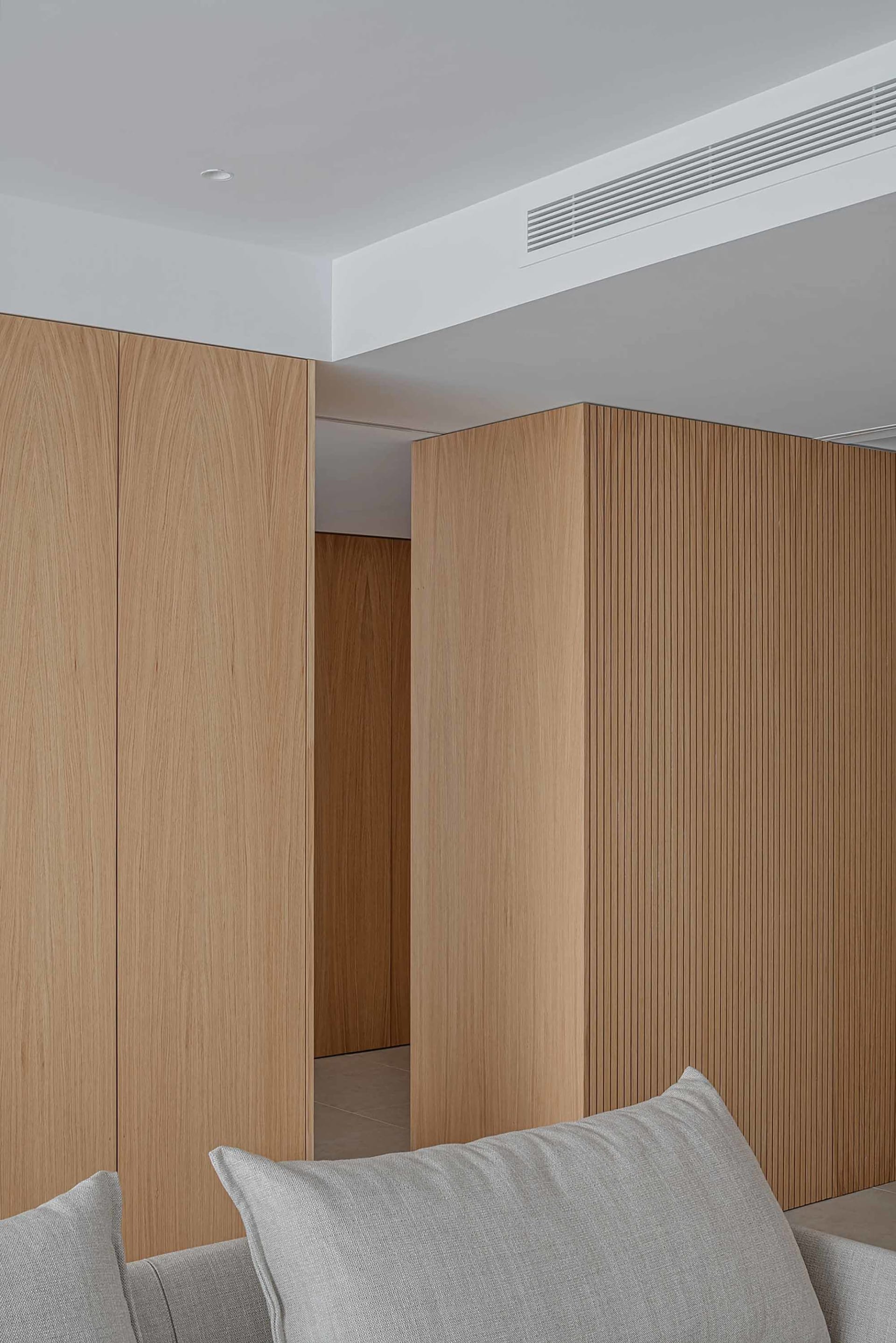 Modern minimalist bedroom featuring sleek, wooden paneling with geometric lines and a neutral color palette.