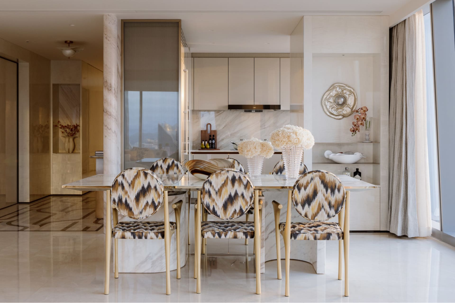 A modern dining room with a marble table and chairs with a geometric pattern.