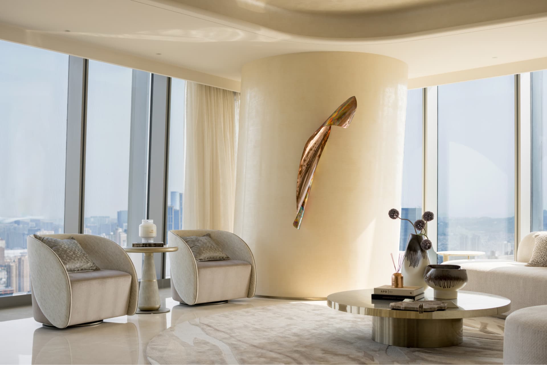 A modern living room featuring sleek glass and concrete elements with a metal sculpture.