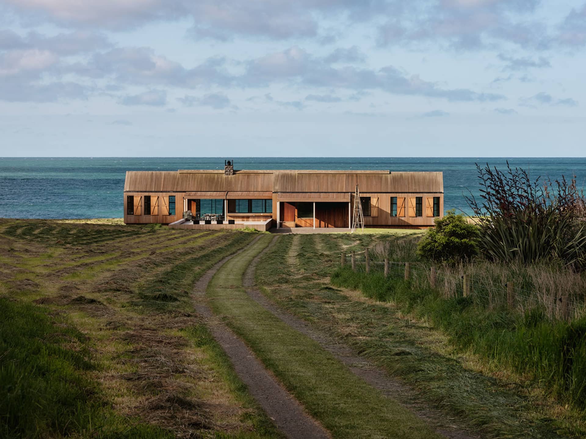 A modern beach house with wooden exterior and ocean view.