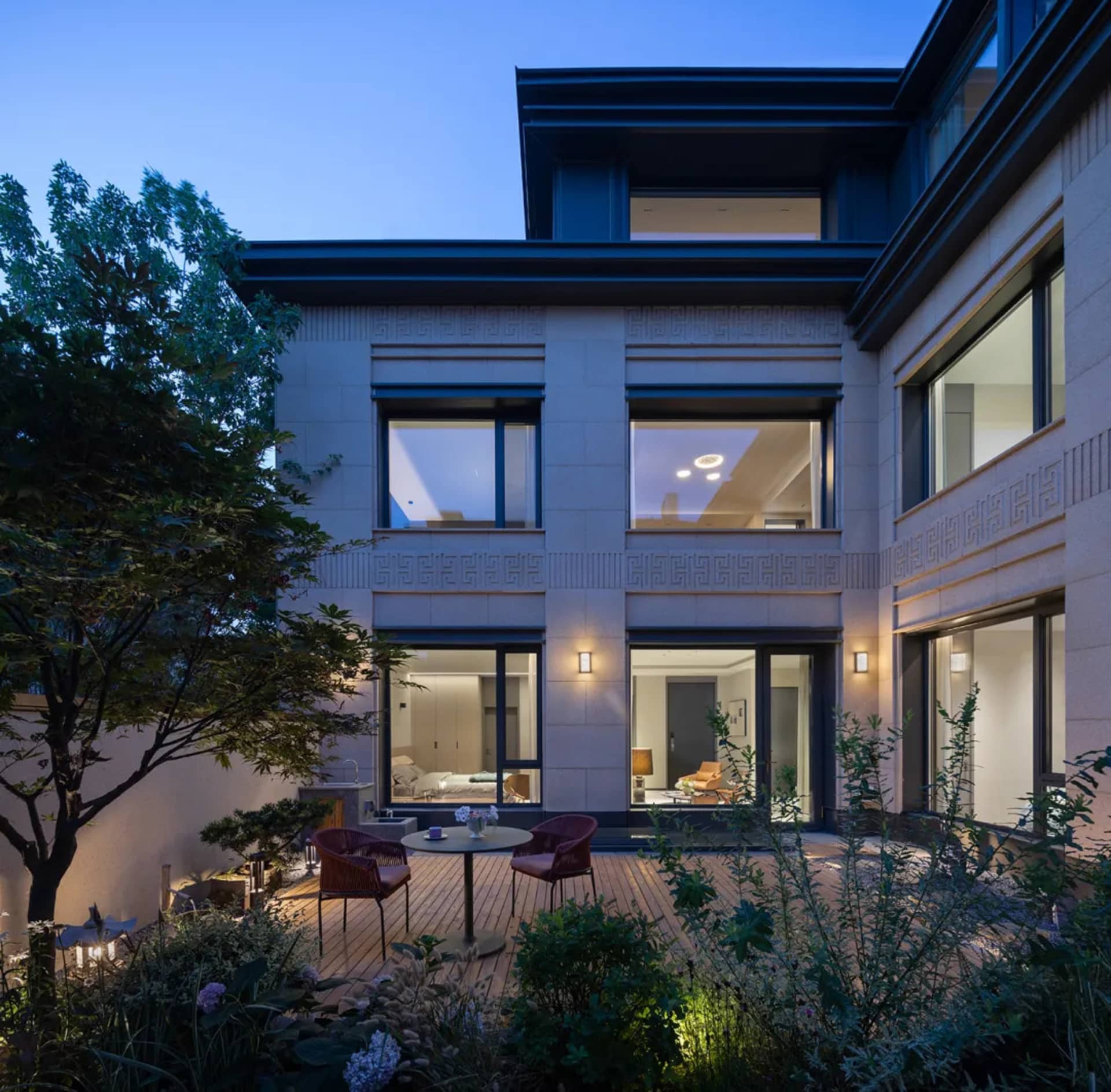 A modern house with concrete exterior walls at dusk with a lit patio area.