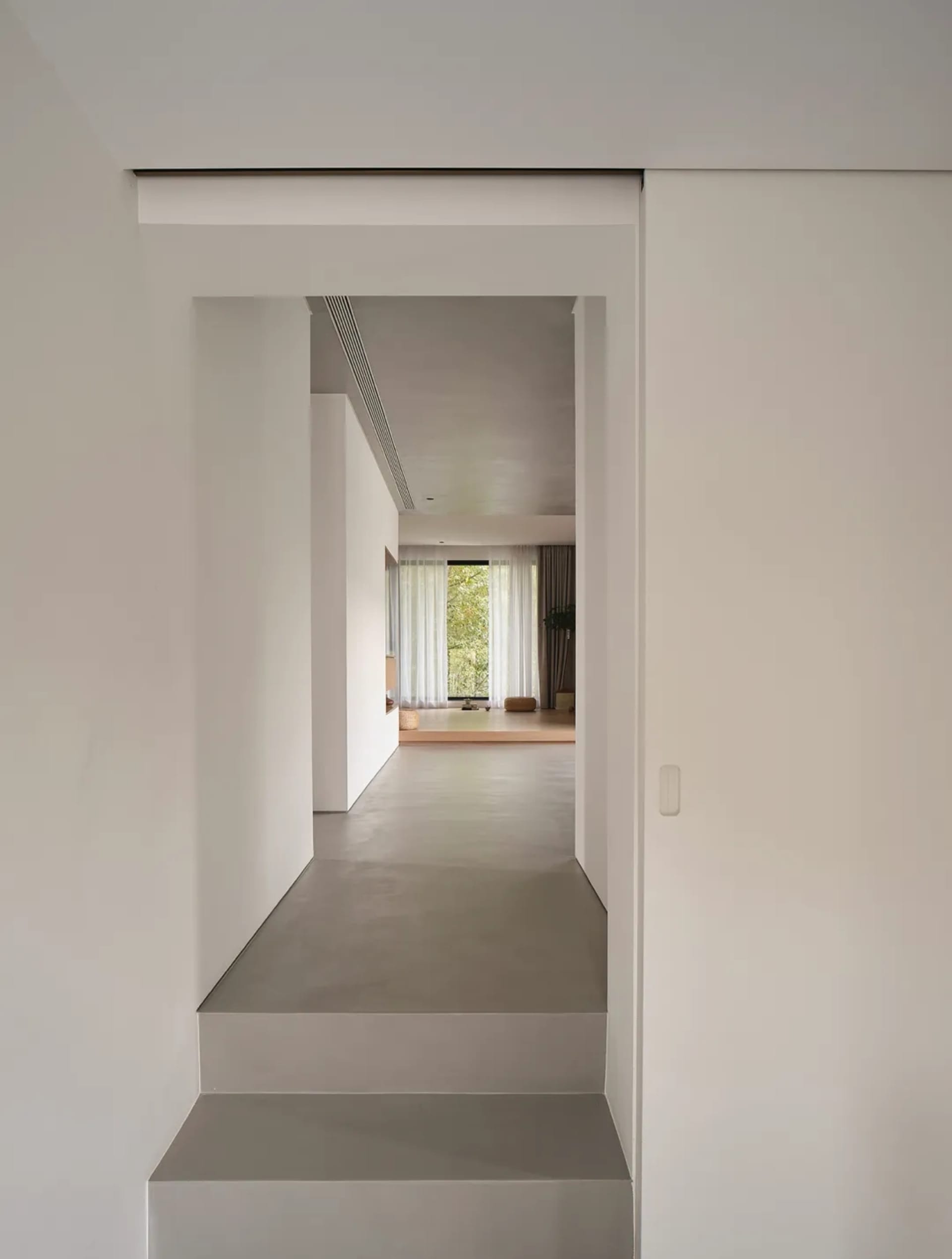Modern living room with concrete flooring, minimalist decor, and white walls.