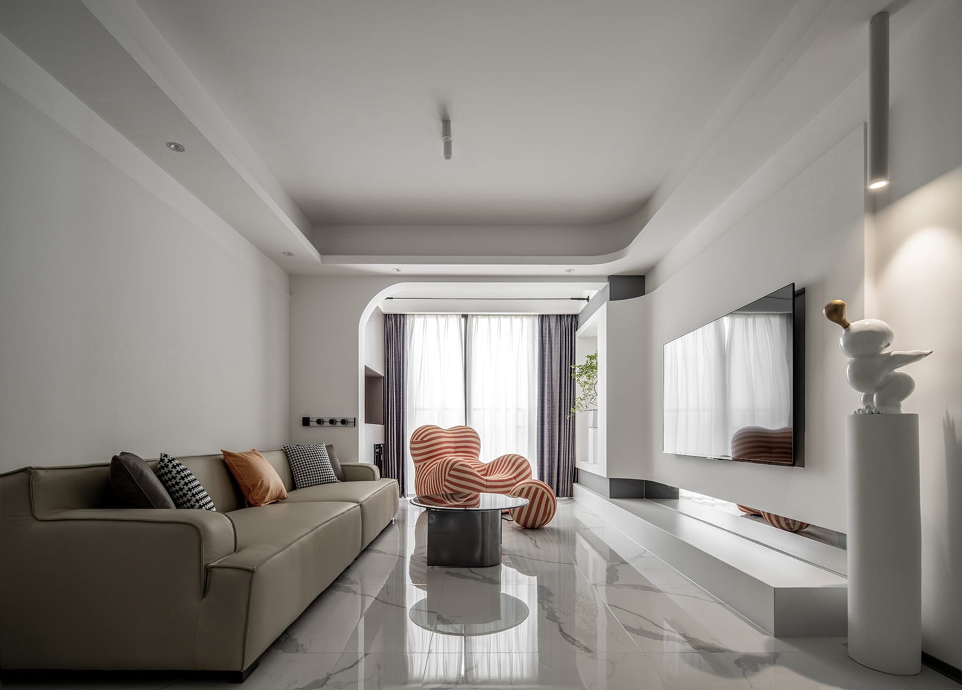 Modern living room with taupe carpet, beige sofa, and white and orange striped armchair.