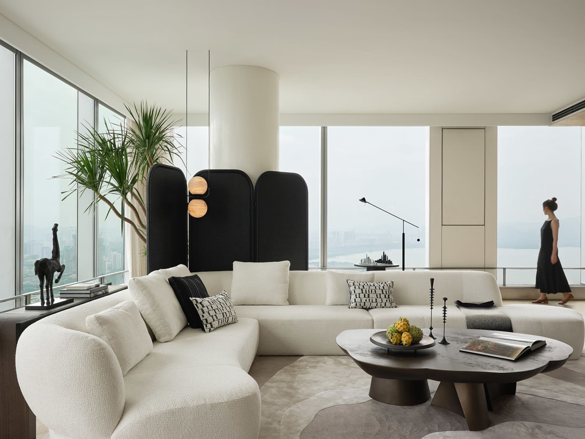 Modern living room with a white fabric couch, minimalistic design, and large windows overlooking a cityscape.