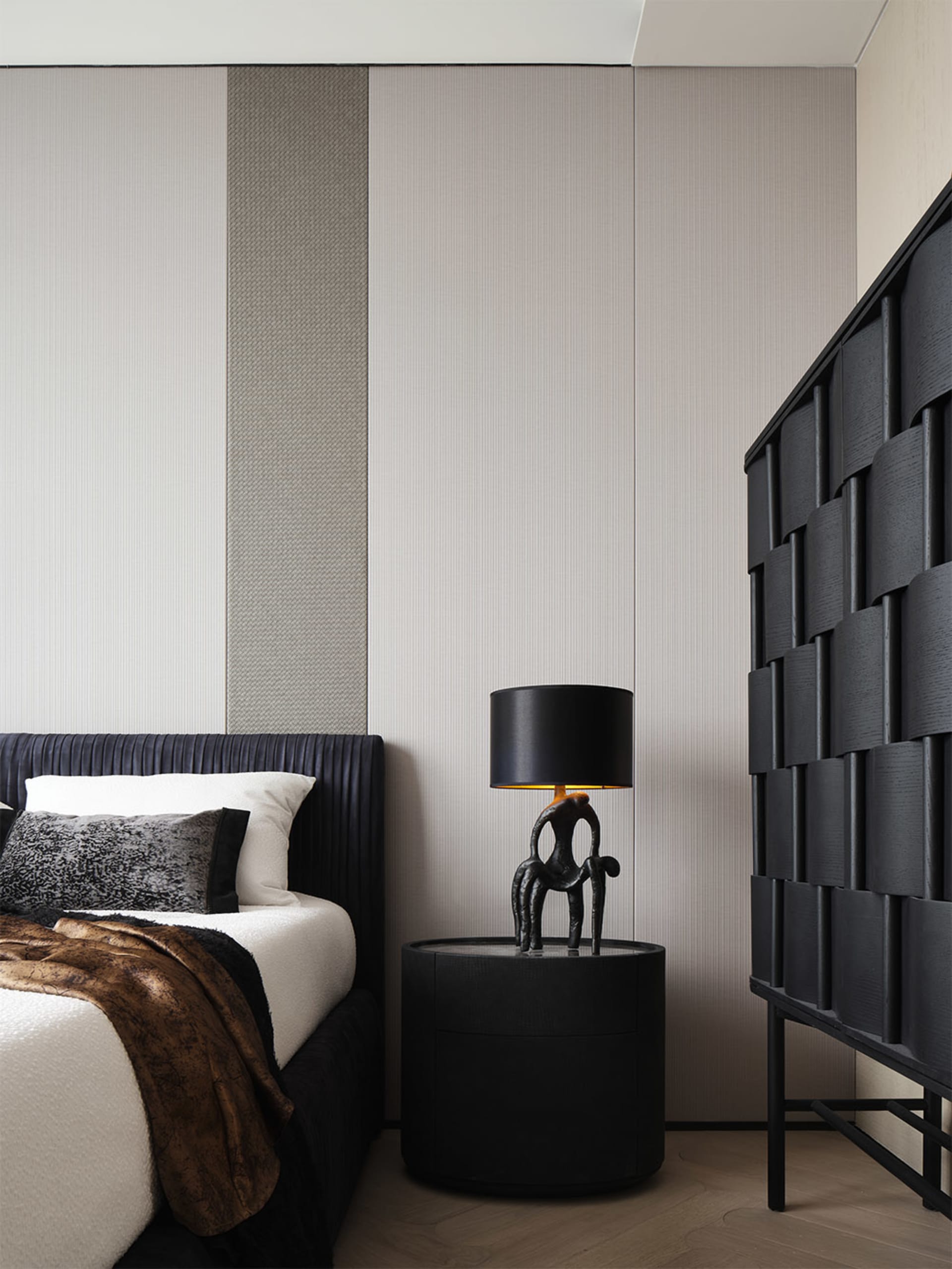 A modern minimalist bedroom featuring sleek, black furniture, a bed with a textured headboard, and a black lamp with a black 