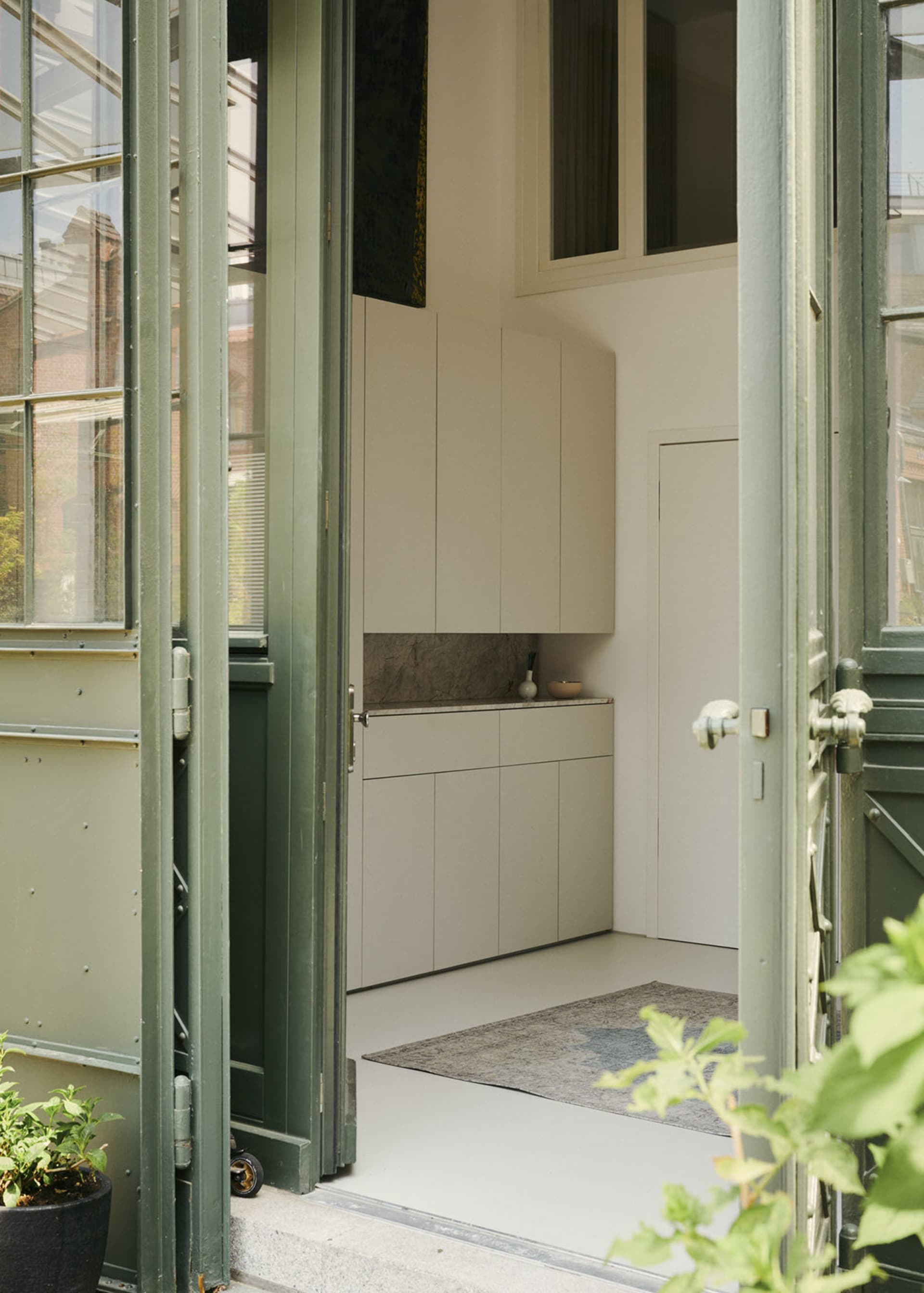 A modern apartment entryway featuring white walls, doors, and cabinets.