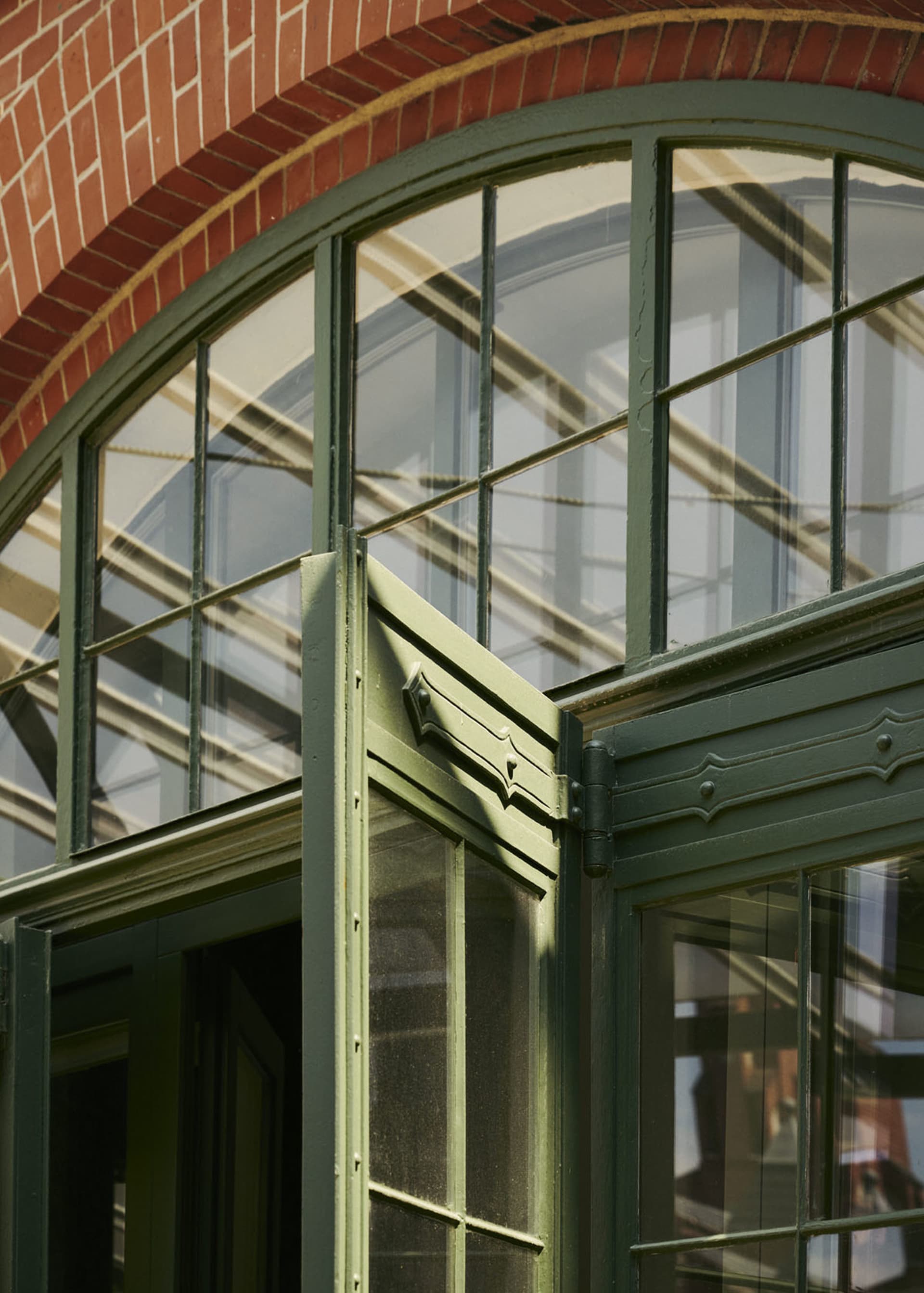 Modern building exterior featuring large glass windows with green frames.